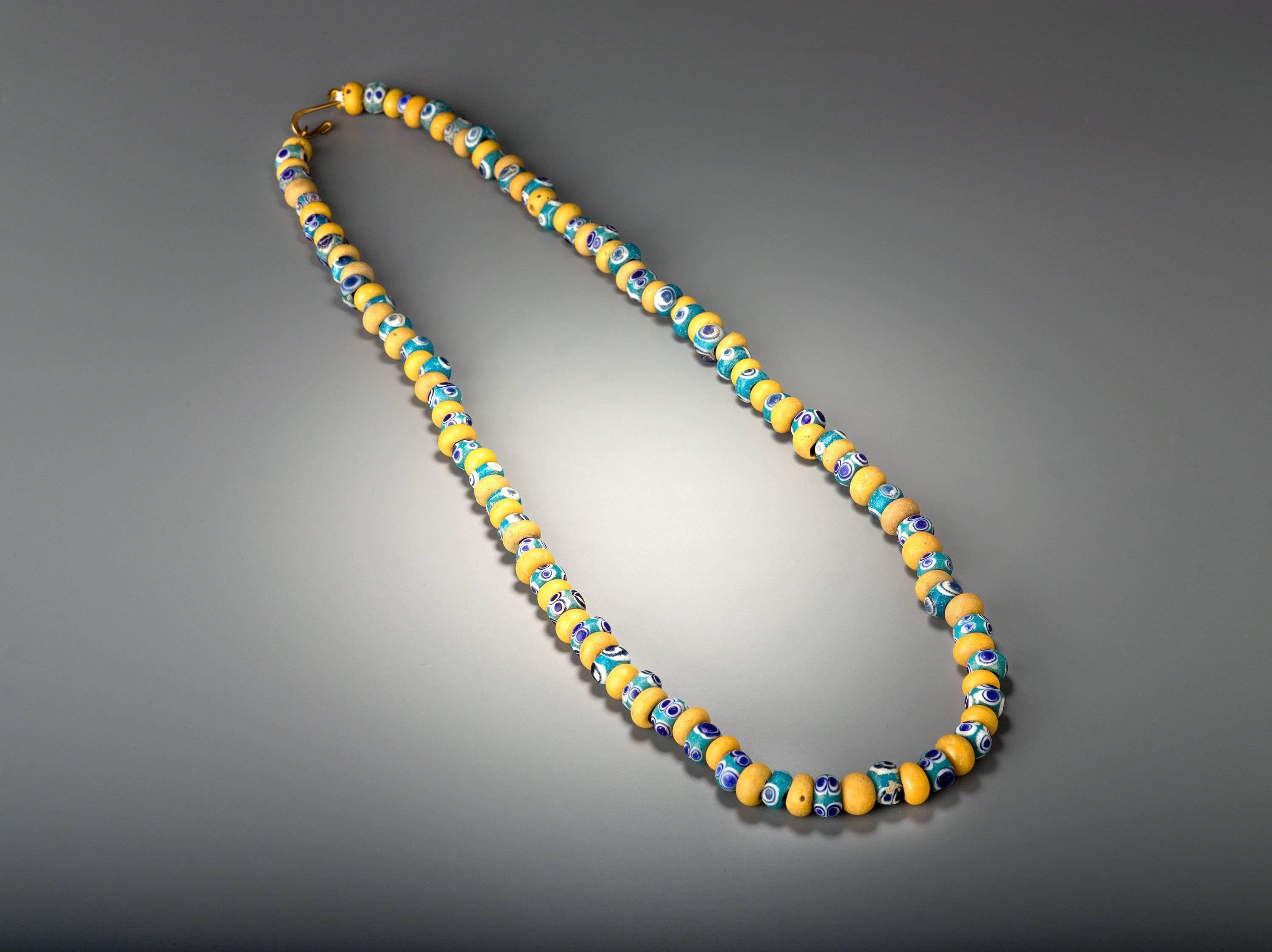 The necklace is composed of turquoise blue and white beads with dark blue eyes. These eye beads are alternated with plain yellow glass beads, an assembly of 120 beads making it to a most desirable and wearable piece of jewelry.
Provenance: Private