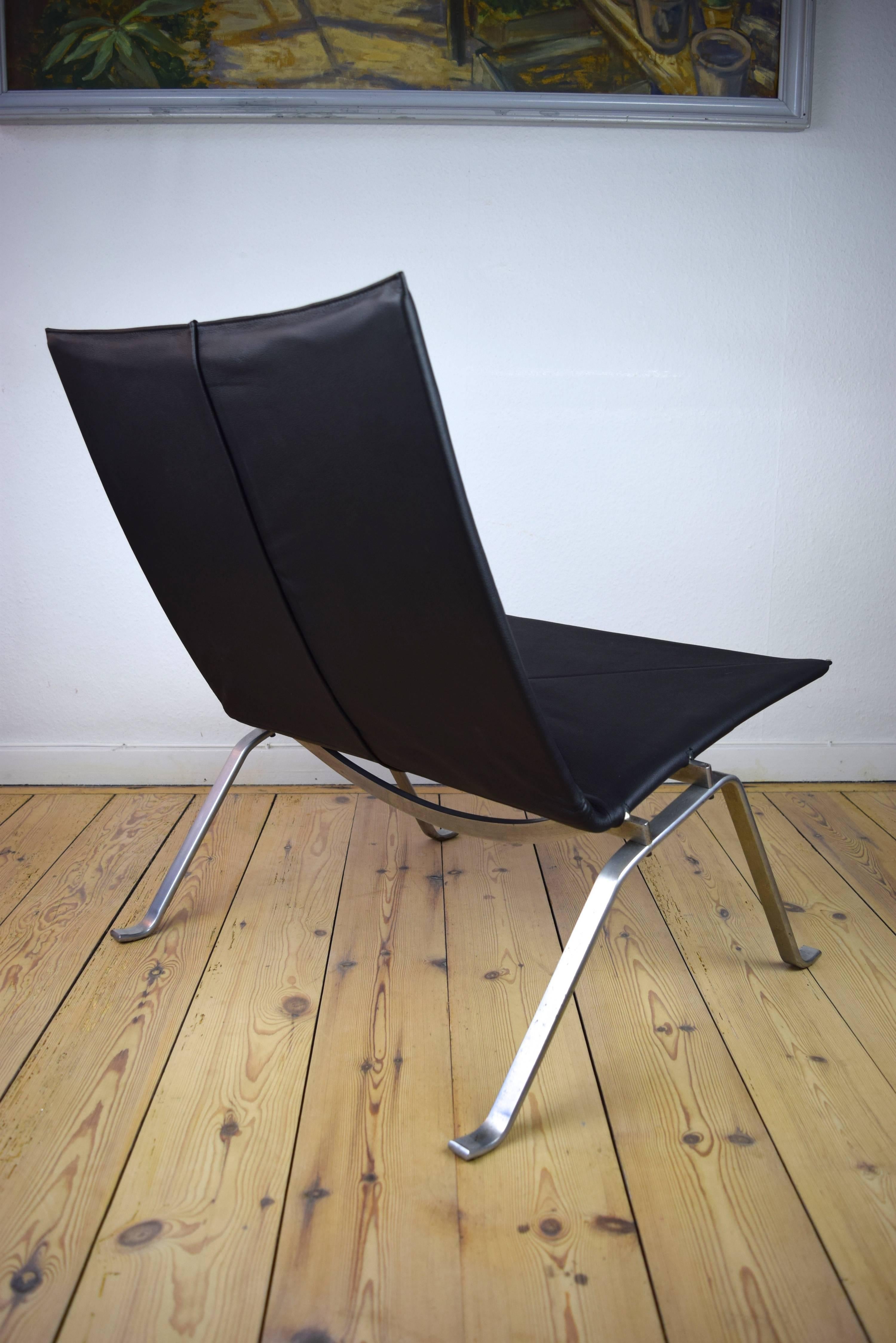 This PK-22 lounge chair was designed by Poul Kjærholm and is one of the original models produced by E.Kold Christensen from the 1950s to mid-1960s. The chair features a matte chrome plated steel base with black leather upholstery.