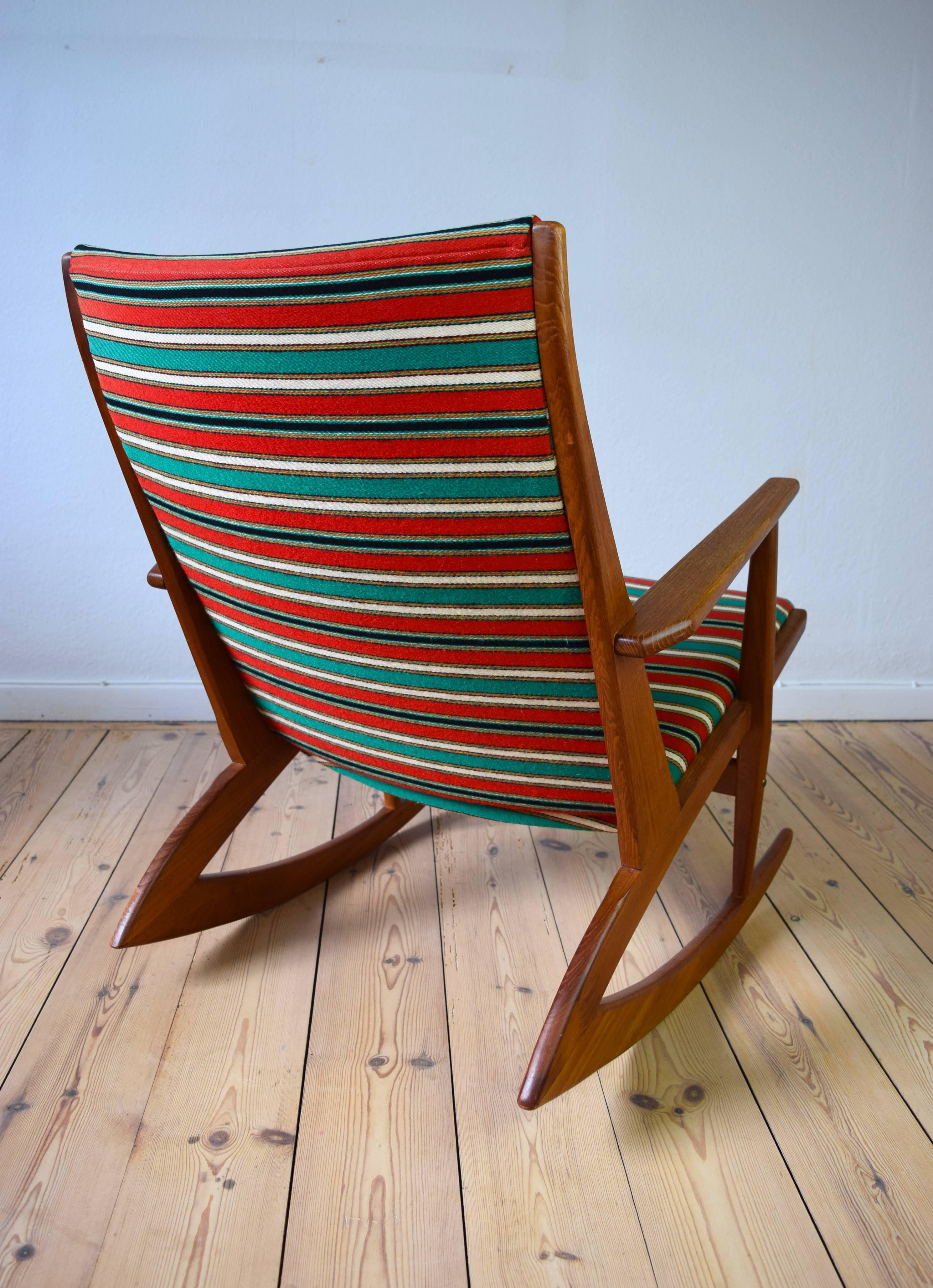 This model 97 Atomic teak rocking chair was designed by Holger Georg Jensen in 1958 and was produced by Kubus in Denmark. The piece features its original red striped fabric and is in a very good vintage condition with minimal wear.