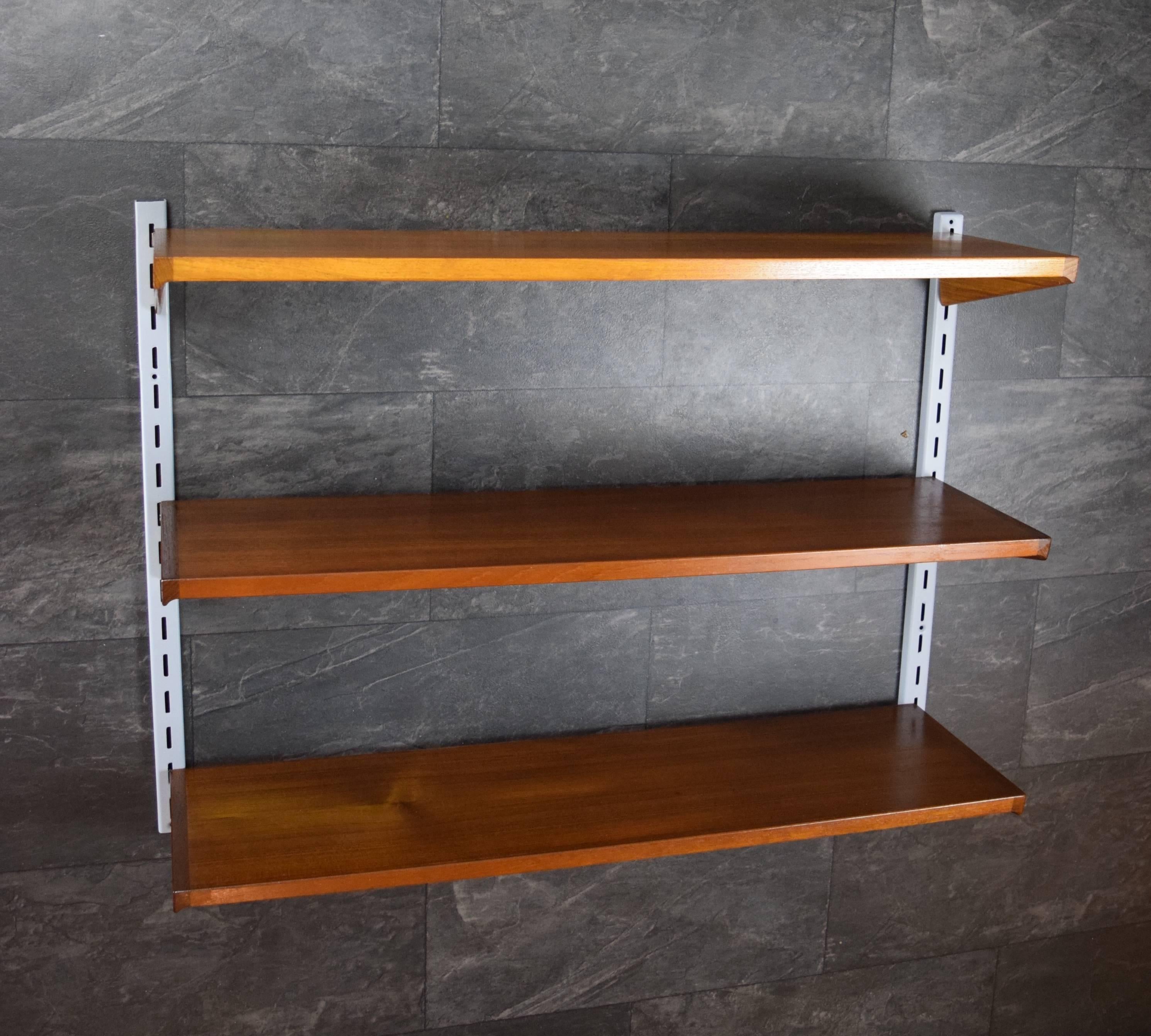 Set of three teak shelves by Kai Kristiansen and manufactured by Feldballes Møbelfabrik, Denmark from the 1960s. This system comprises of three shelves and two metal hanging rails.