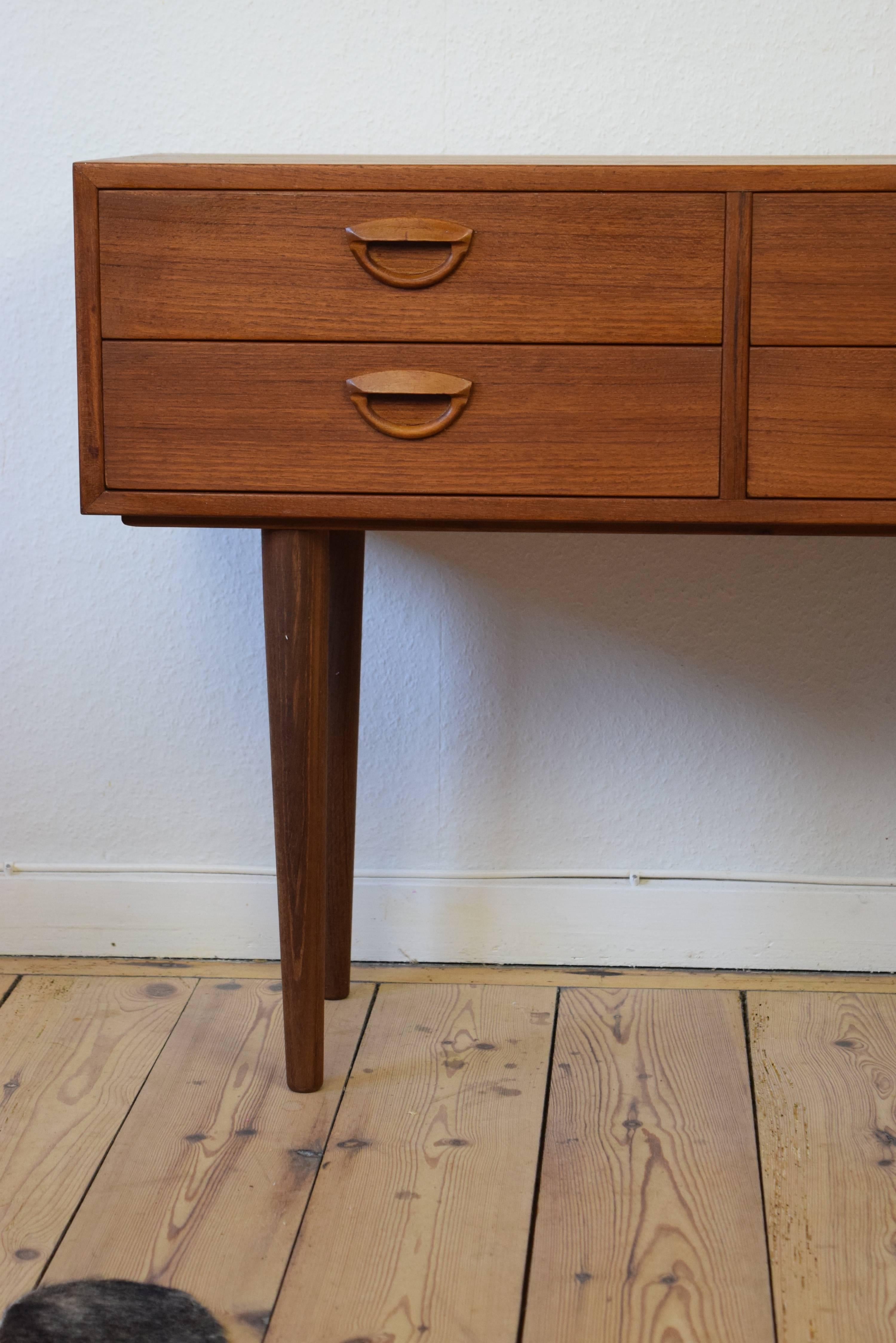 This small entry chest was manufactured by Feldballes Møbelfabrik and designed by Kai Krisitiansen in Denmark in the 1960s. It features four drawers and sits on long tapered solid teak legs.