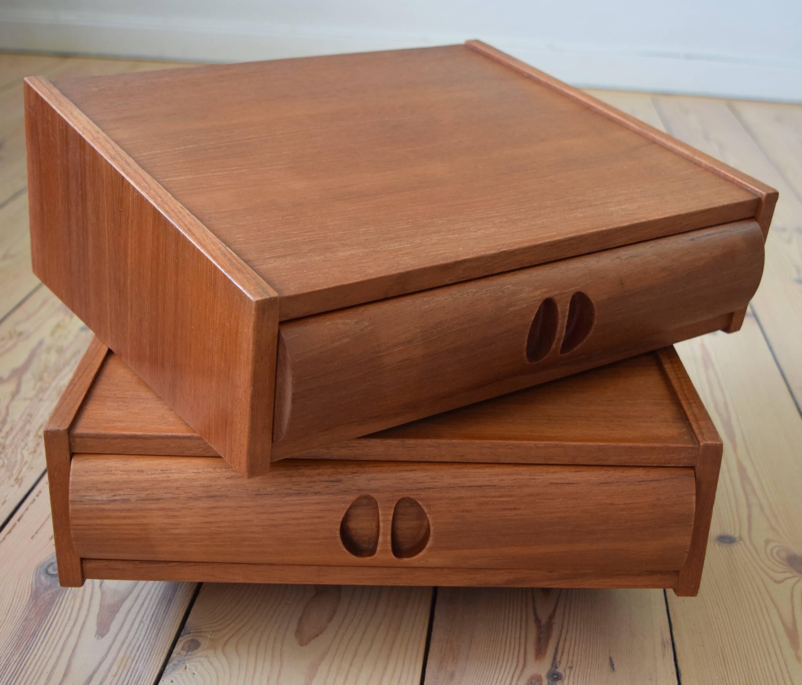 Two teak night tables manufactured in Denmark in the 1960s. This lovely pair can be attached to a wall or headboard using screws and/or dowels. Features a curved piece of solid teak on the front of the drawer with recessed drawer pulls.