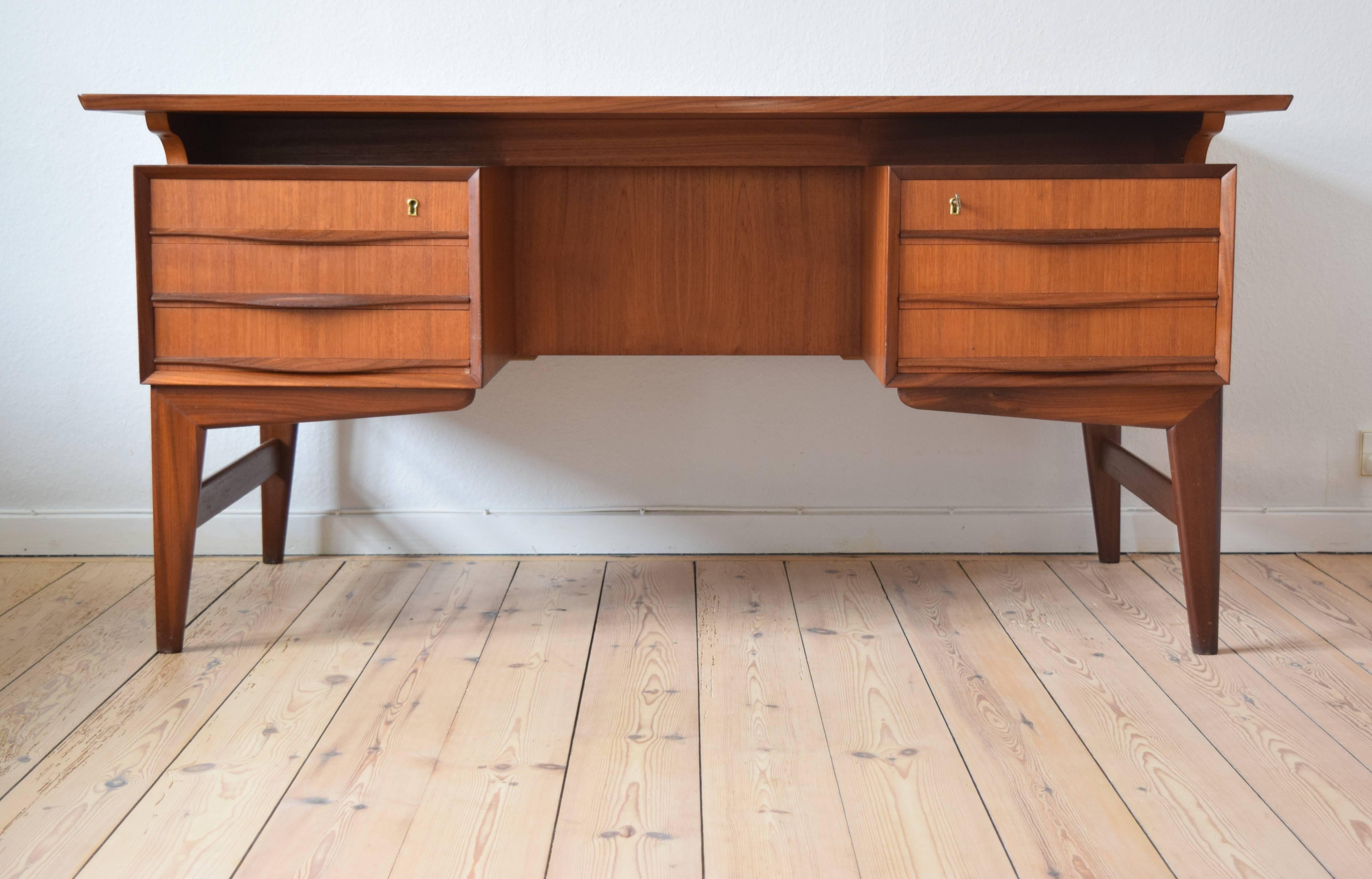 Teak executive floating desk from the 1960s manufactured in Denmark. This piece features six drawers, offering plenty of storage in the front and back. Two lockable drawers. Sits on a 'boomerang leg' base. The teak on the desk is in a fantastic