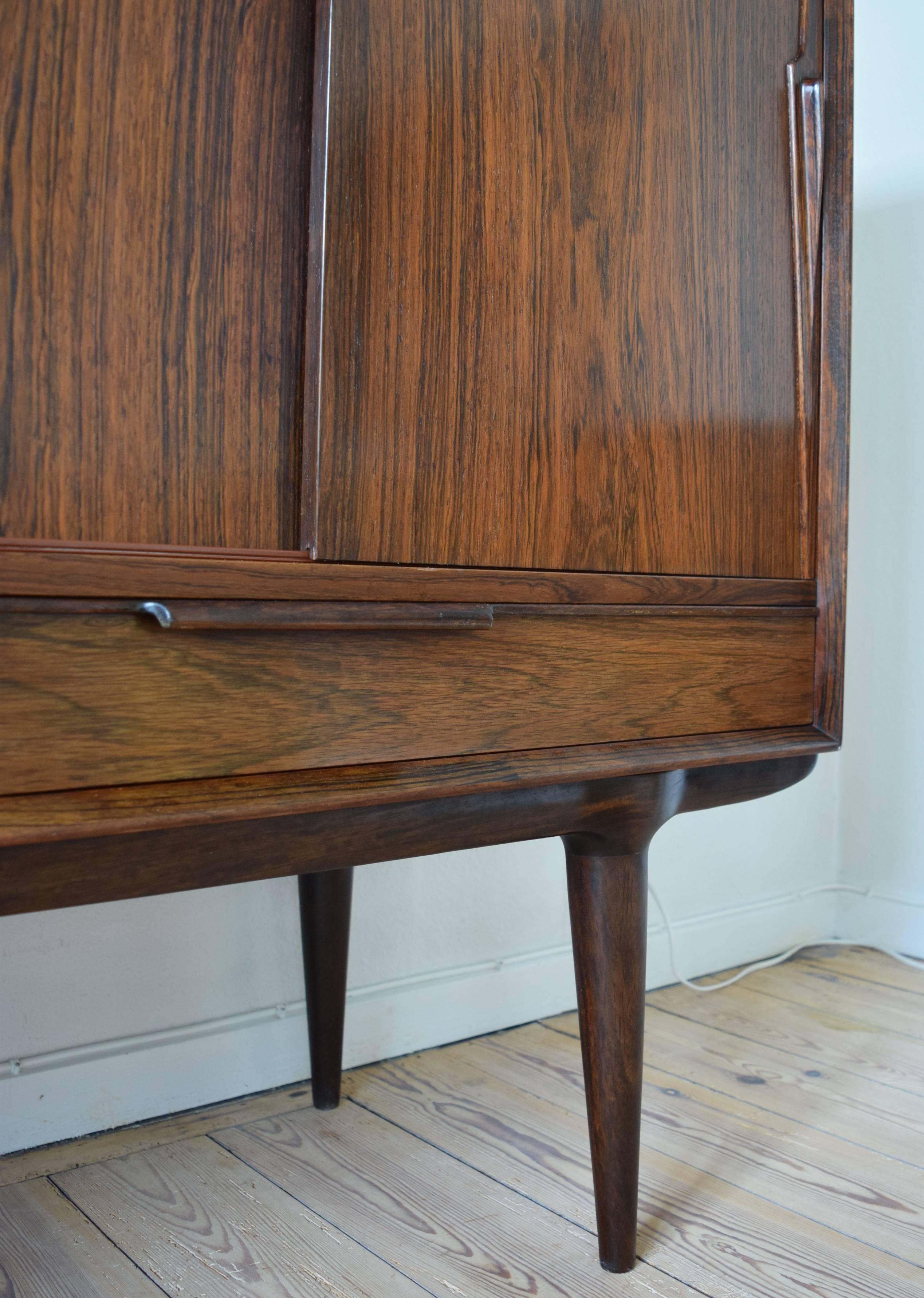 Iconic rosewood credenza manufactured by Omann Jun of Denmark in the 1960s. This particular piece in in a very good condition for its vintage and features four sliding doors and two smooth drawers. Inside are more drawers and shelves with the