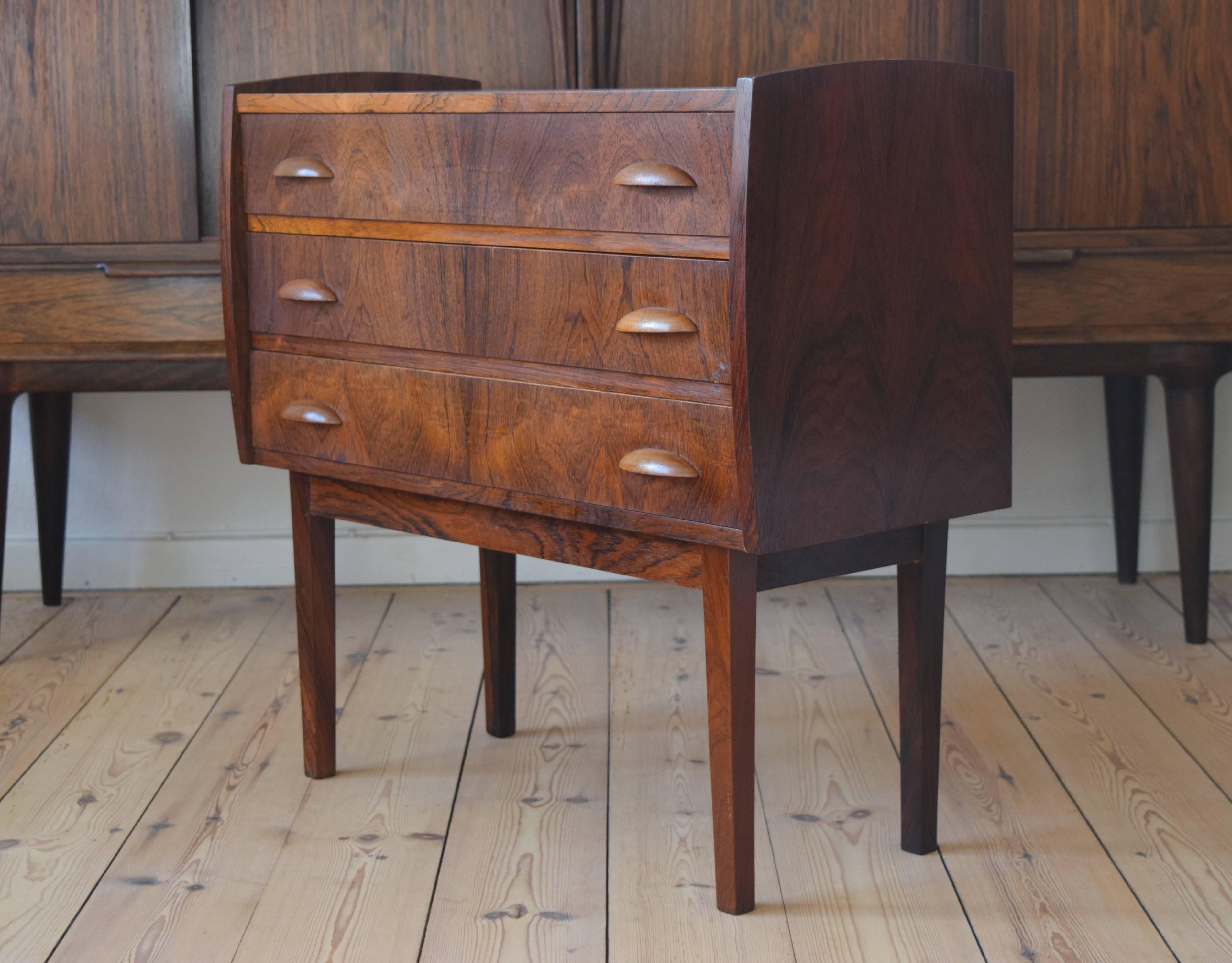 Small three-drawer chest designed and manufactured in Denmark in the 1960s. Features teak orange slice handles and sits on a solid rosewood and veneer frame base. Striking grain throughout.