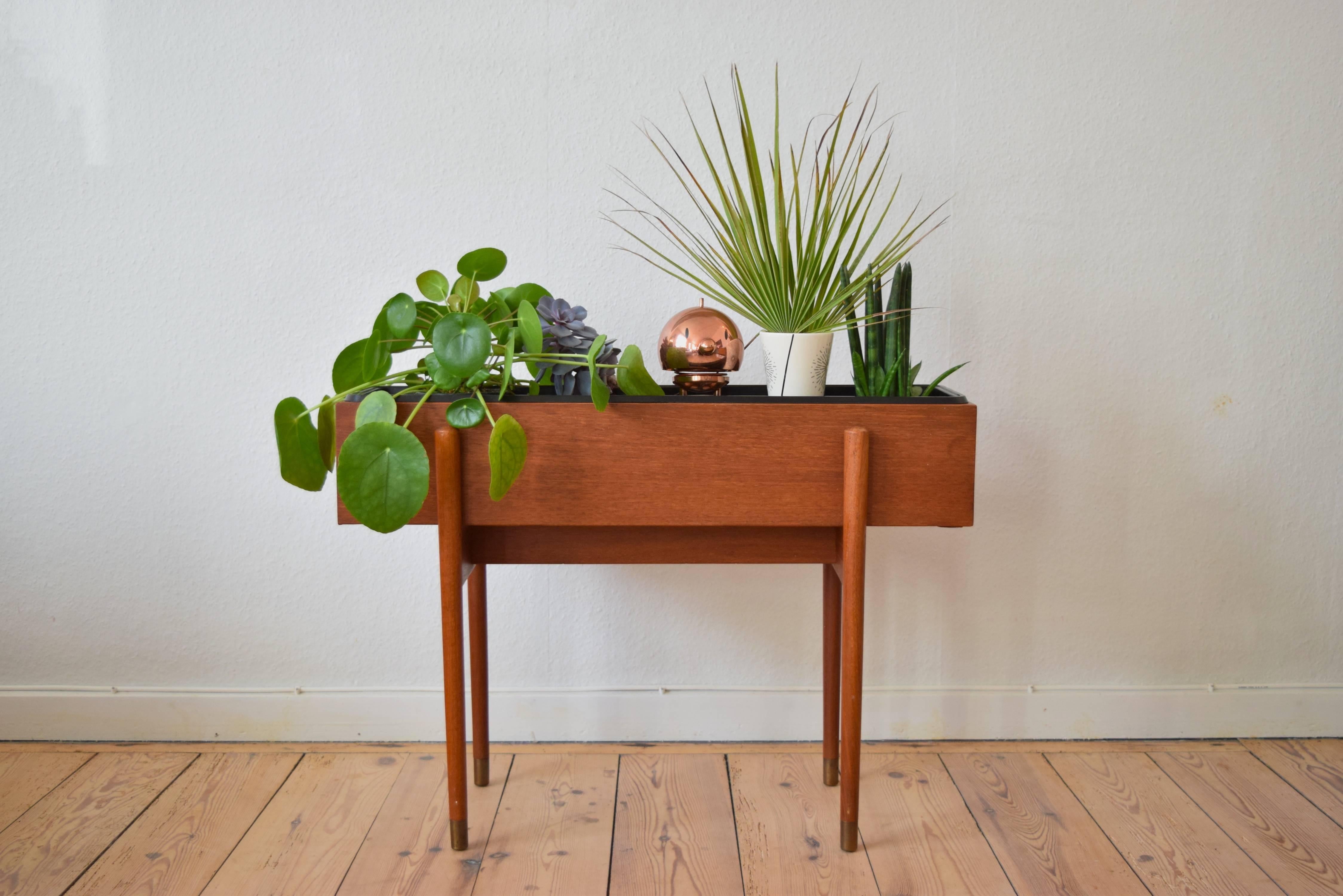 Teak planter designed and manufactured in Denmark in the 1960s. Plant holder sits on solid teak frame base and includes original plant insert
This item is in a very good vintage condition with few marks.