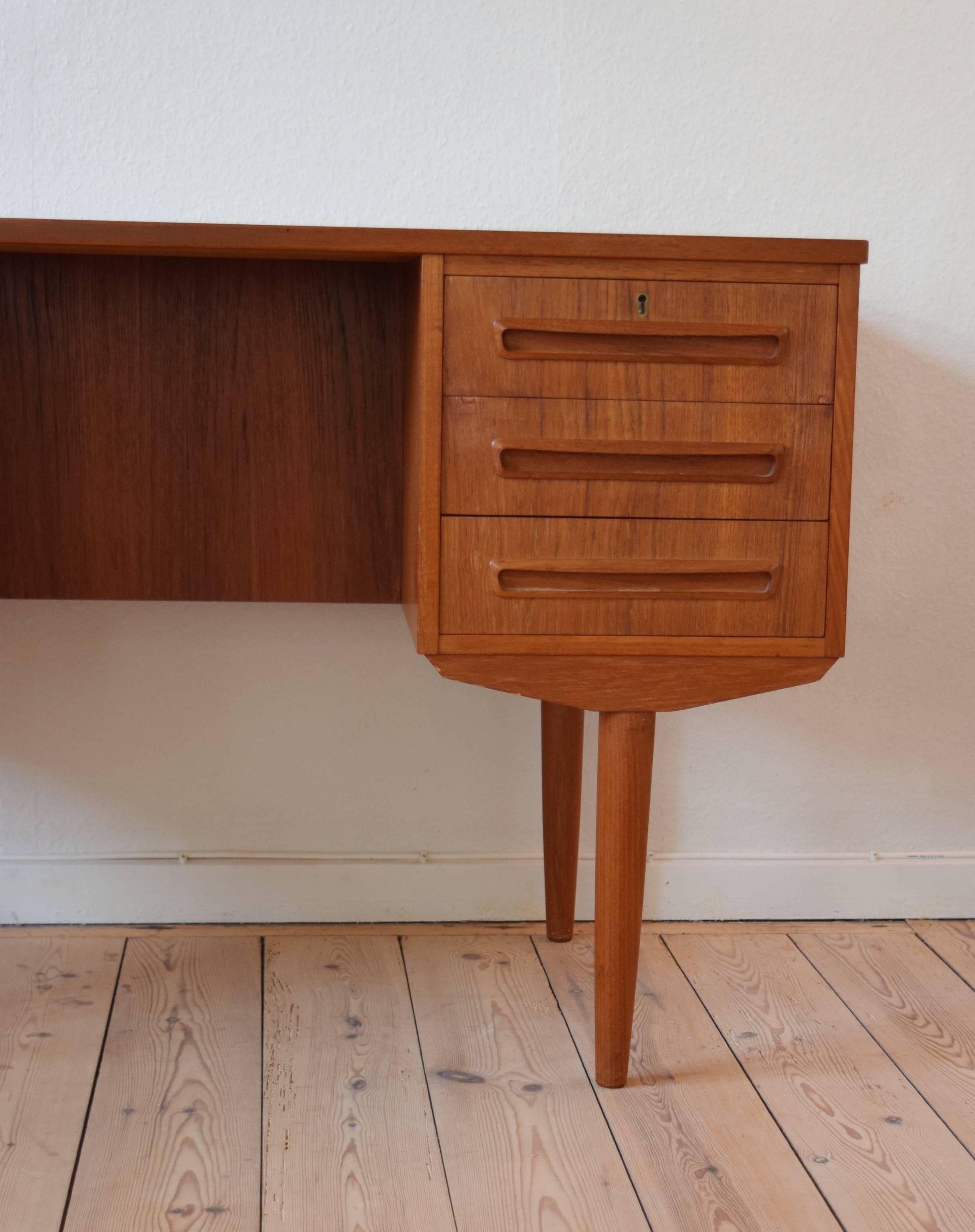 Teak desk designed by J. Svenstrup for A.P. Møbler, Denmark in the 1960s. Desk features six drawers (two lockable) on the front, and shelves on the back side. Very few marks on this item considering it's vintage. Top plate has been refinished and