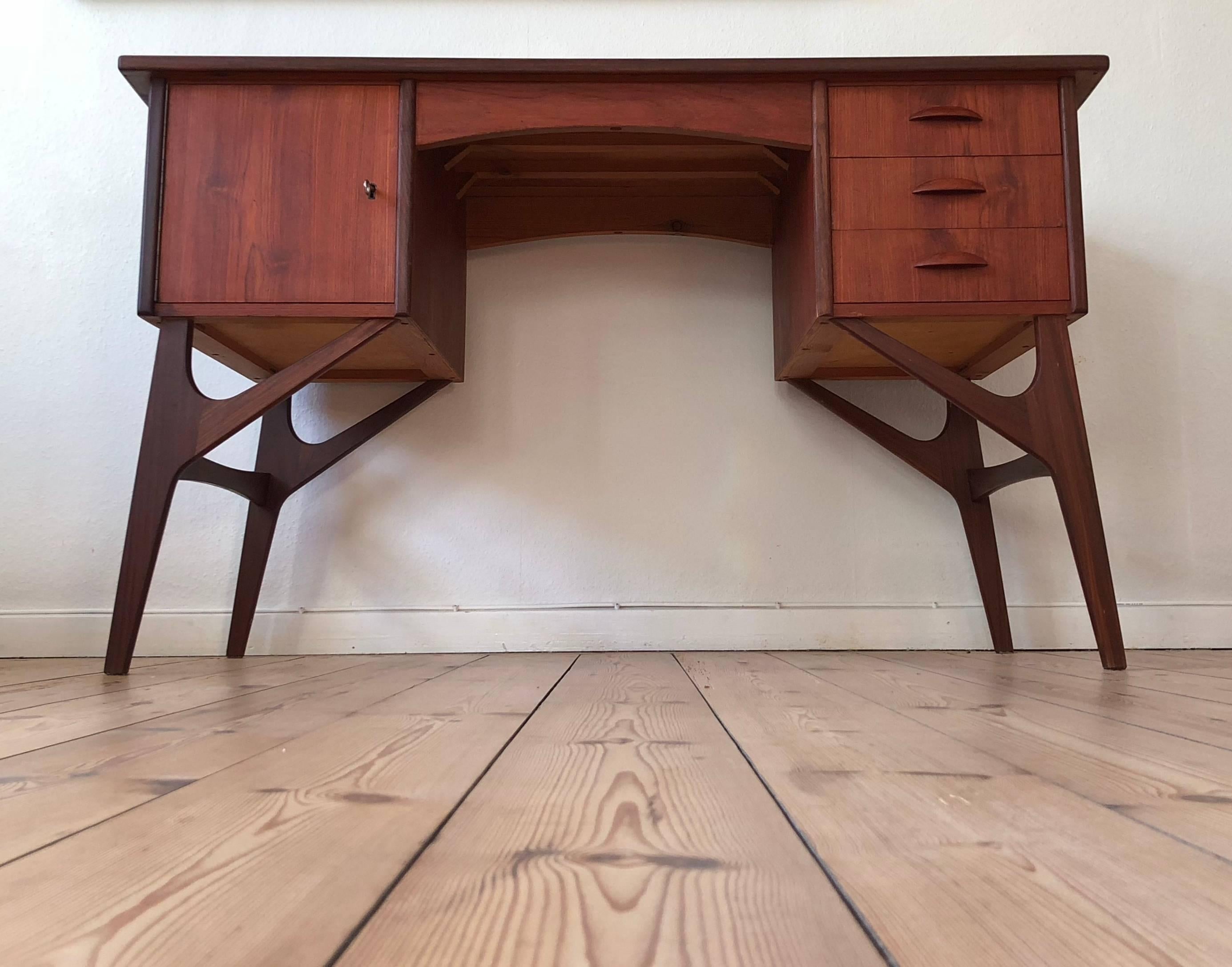 Danish teak desk from the 1950s with matching teak grain on the front, and features three drawers and a maple lined bar cabinet. Sits on inverted ypsilon shaped legs. Some marks on top plate as you would expect from a desk of this vintage, but