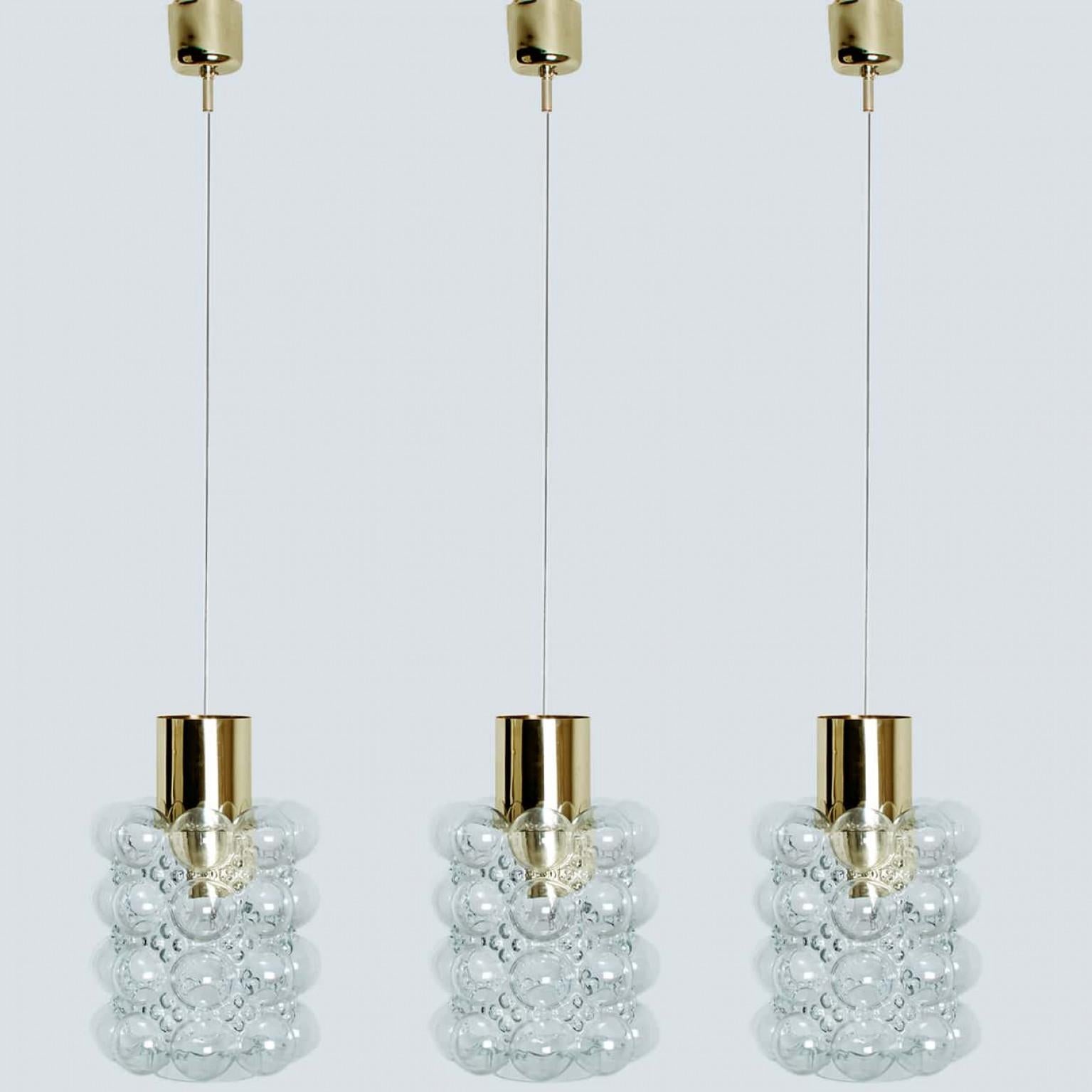 1 delle 3 bellissime lampade a sospensione in vetro a bolle disegnate da Helena Tynell per Glashütte Limburg, 1960. Un design di classe con dettagli color ottone, il vetro soffiato a mano dona una luce meravigliosa.

Helena Tynell è una designer di