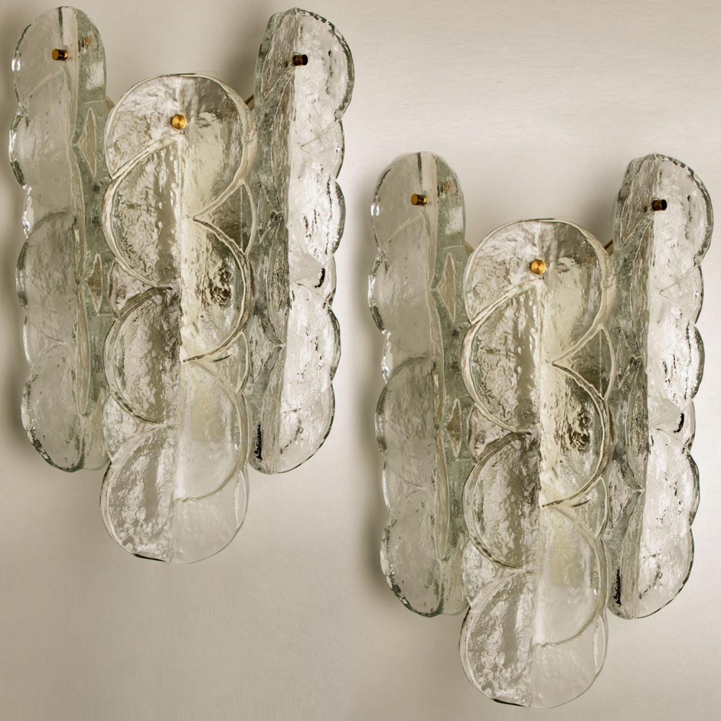 Coppia di appliques Kalmar con vetro opalino chiaro e testurizzato. Il bellissimo e spesso vetro testurizzato è completato dalla ferramenta cromata. Design semplice e pulito. Soffiato a mano, realizzato in vetro trasparente. Apparecchi di alta