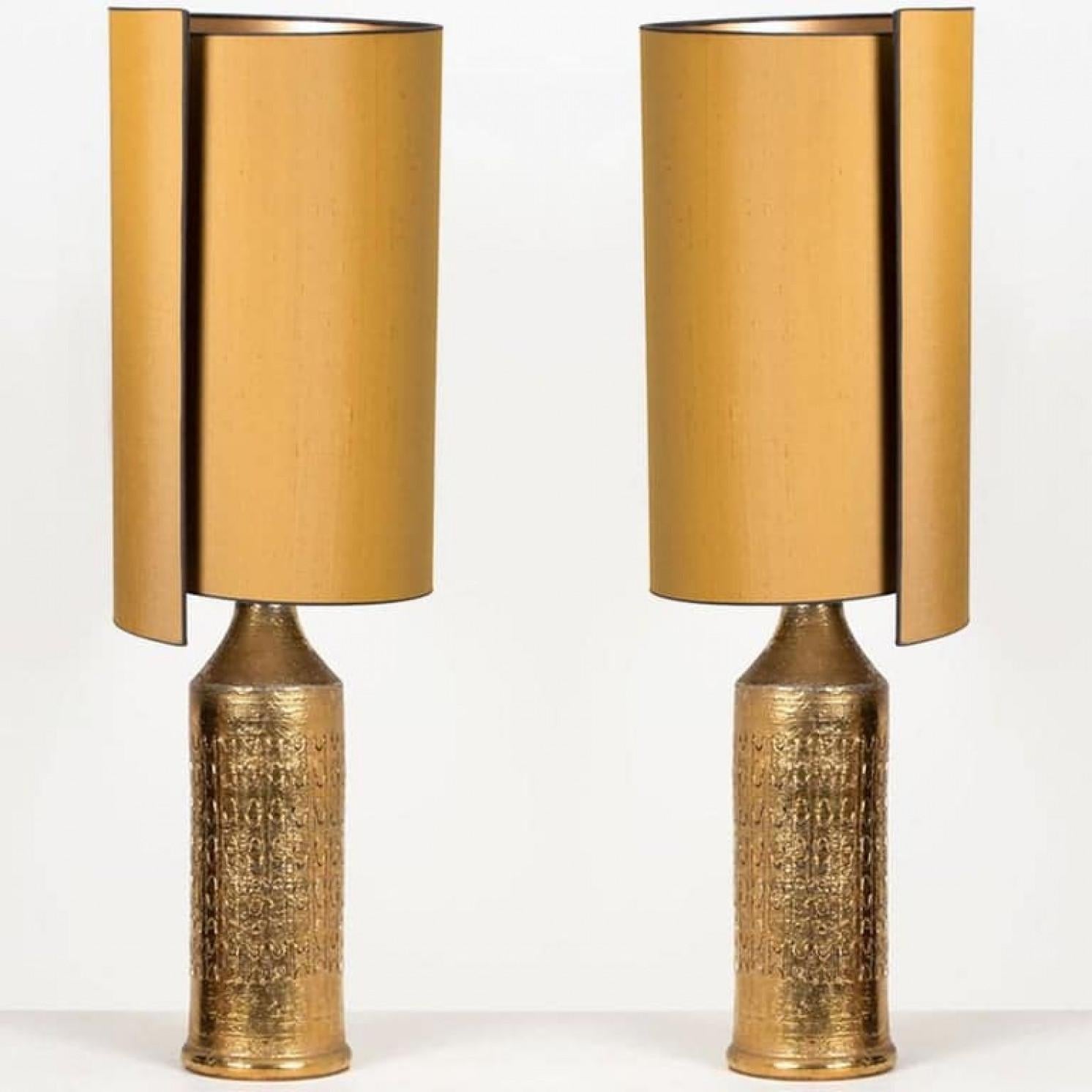 1 of the 2 elegant table lamps. Each lamp features a ceramic base with a rough surface in an off-white glaze with shiny metallic gold glazed patterns, Bitossi, Italy, circa 1960s. With exceptional new custom made silk shades by René Houben. With