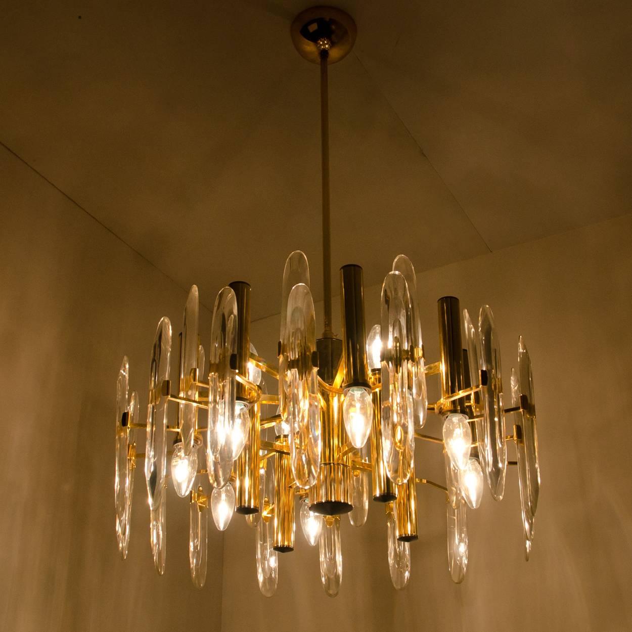 This chandelier was designed by Gaetano Sciolari and was produced in Italy in the 1960s. The two-tiered brass base frame is surrounded by crystal glass vertical shards. The crystals are meticulously cut in such a way that radiate the light of the