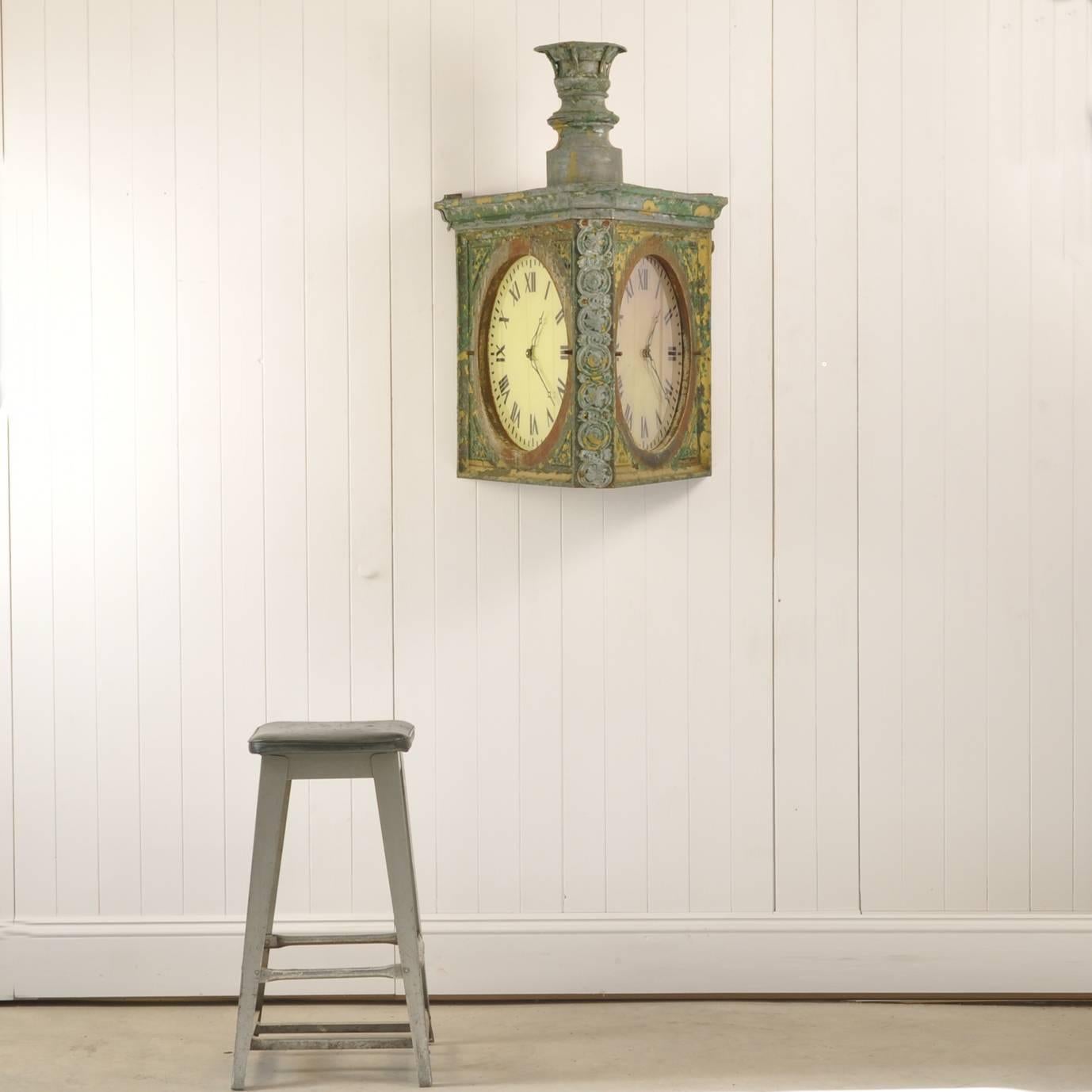 This is first time we have seen a clock like this. It is double sided and would have been wall-mounted. It is late 19th century, Dutch. 

The body is cast iron with a lead relief down the front and the top and the chimney is zinc. Originally this