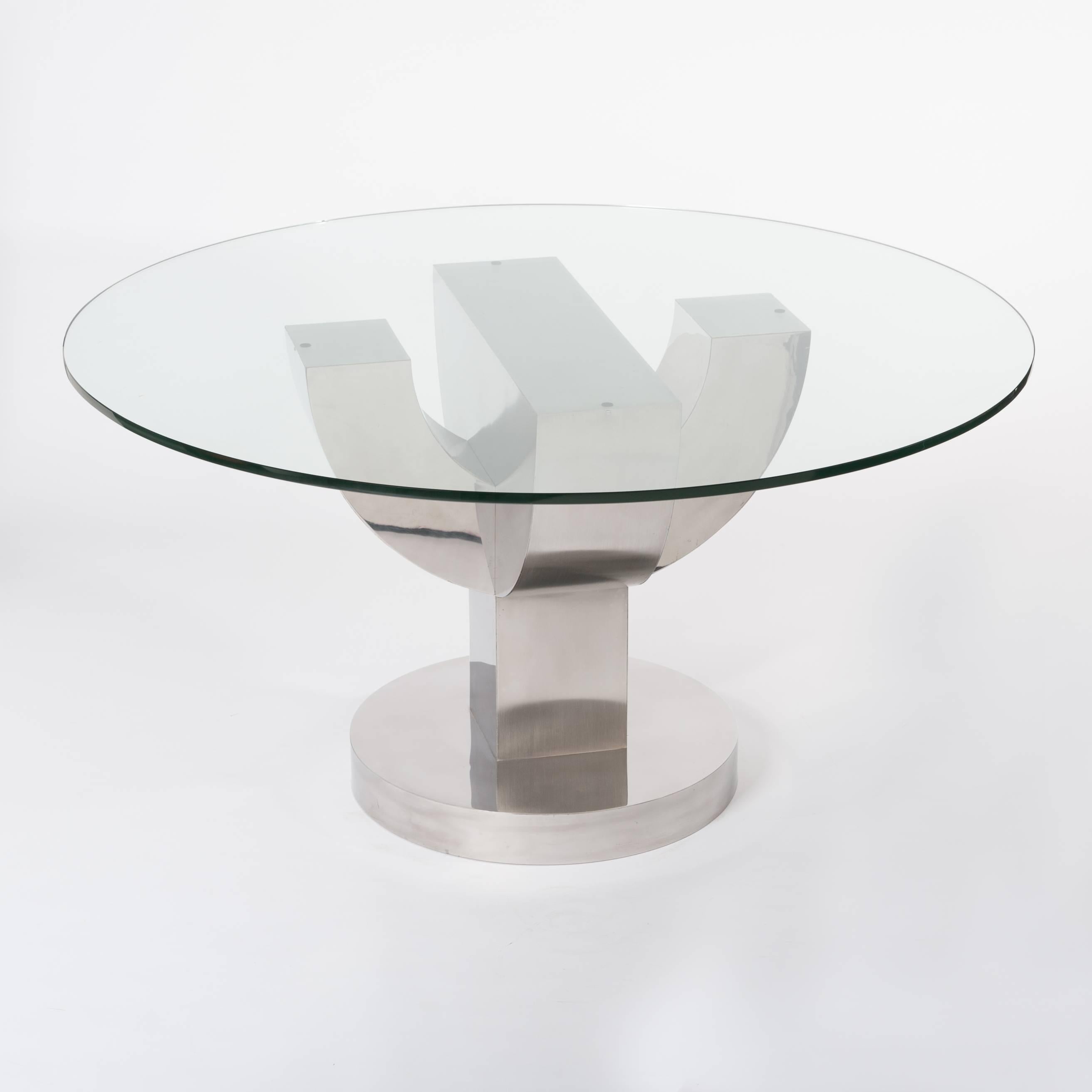 Exceptional round dining table with thick glass top and base made of solid wood veneered with stainless steel. 
The processing of the veneer of thin stainless steel pallets consists of alternating matte and shiny parts, that's why the table is