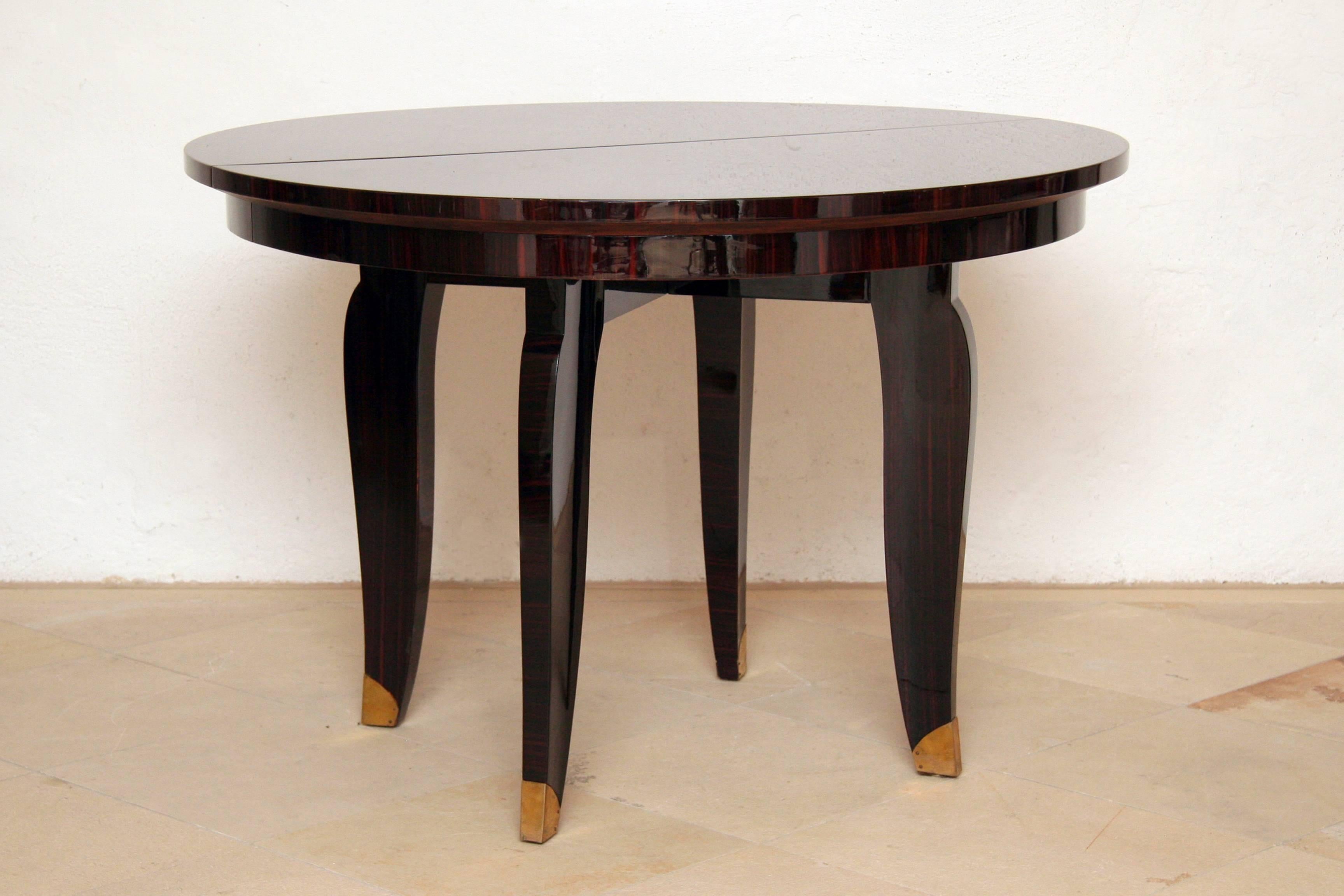 Elegant French Art Deco round dining table (extendable) or center table with wonderful warm and brilliant Macassar ebony veneer, four tapered Macassar wood legs with bronze trimming. Signed by stamp NANCY 1935
The grain of the Macassar veneered