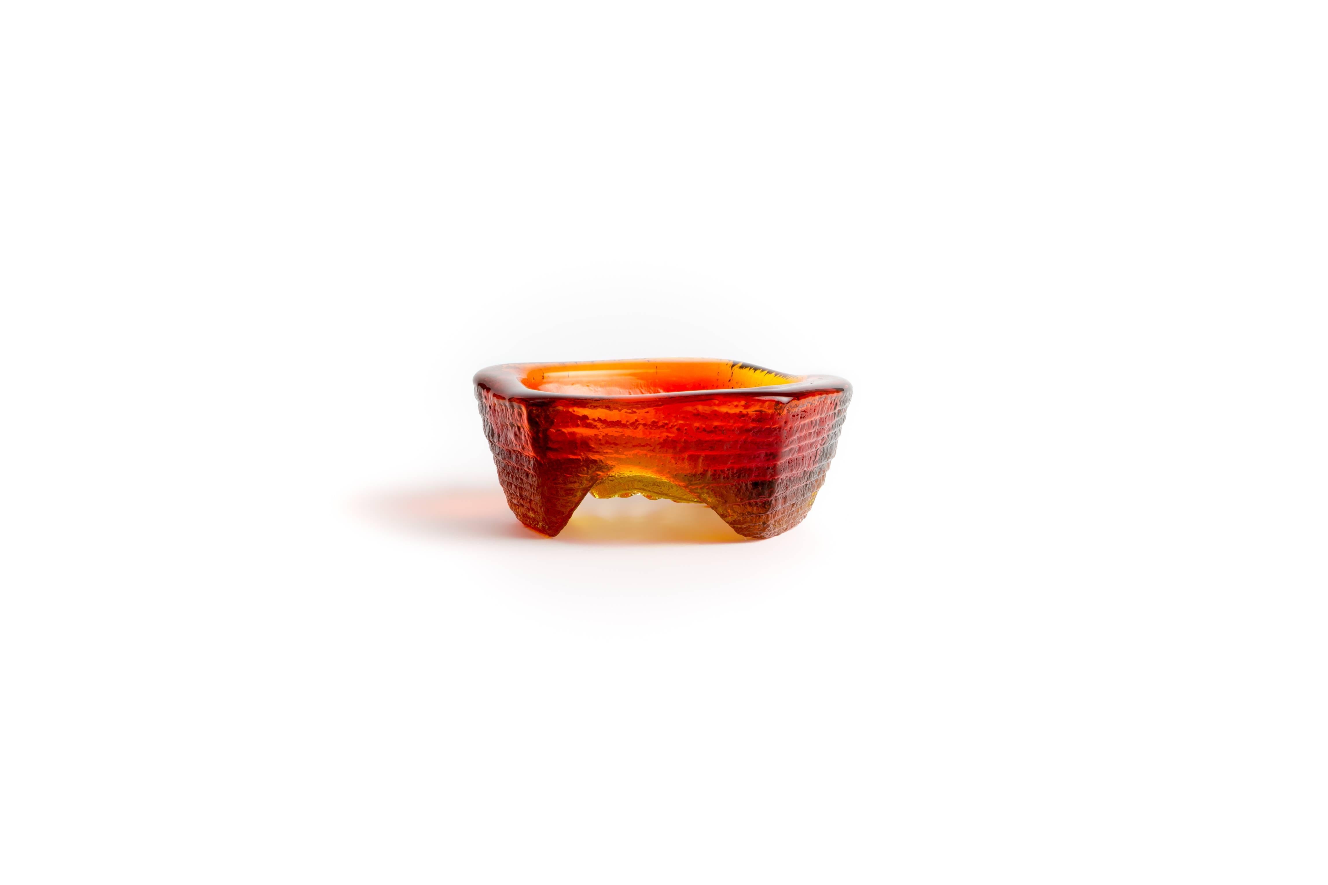 This is a (five) sided red and yellow bowl with legs that elevate it and a unique pattern cast on the bottom.