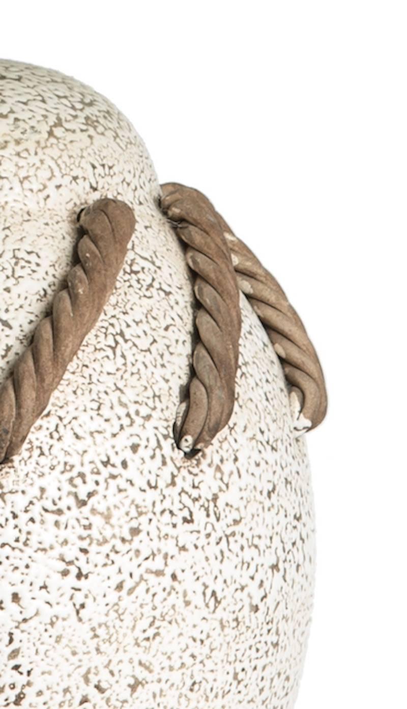 Textured table lamp in brown and white glazes with dimensional rope motif around the body.

Retrofitted with a stepped bronze base.
Wired to US standards.
Shade offered at additional cost.