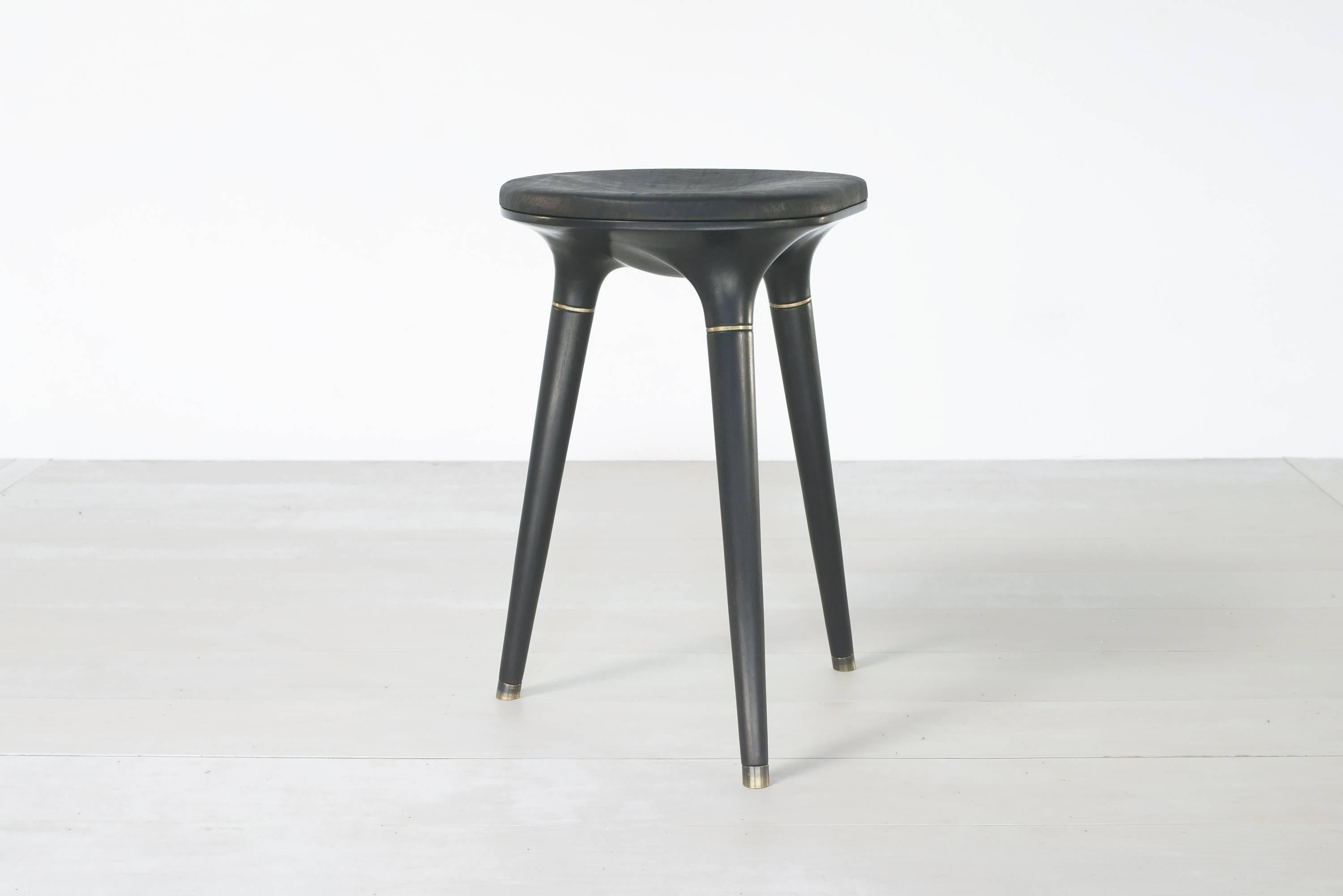 Ebonized stool 001 from Series 001 by Vincent Pocsik.

Carved walnut stool with leather cushion top and brass accents. Shown here in a ebonized finish at counter height. 

Brass feet to have custom felt insets. 

Vincent Pocsik finds the balance