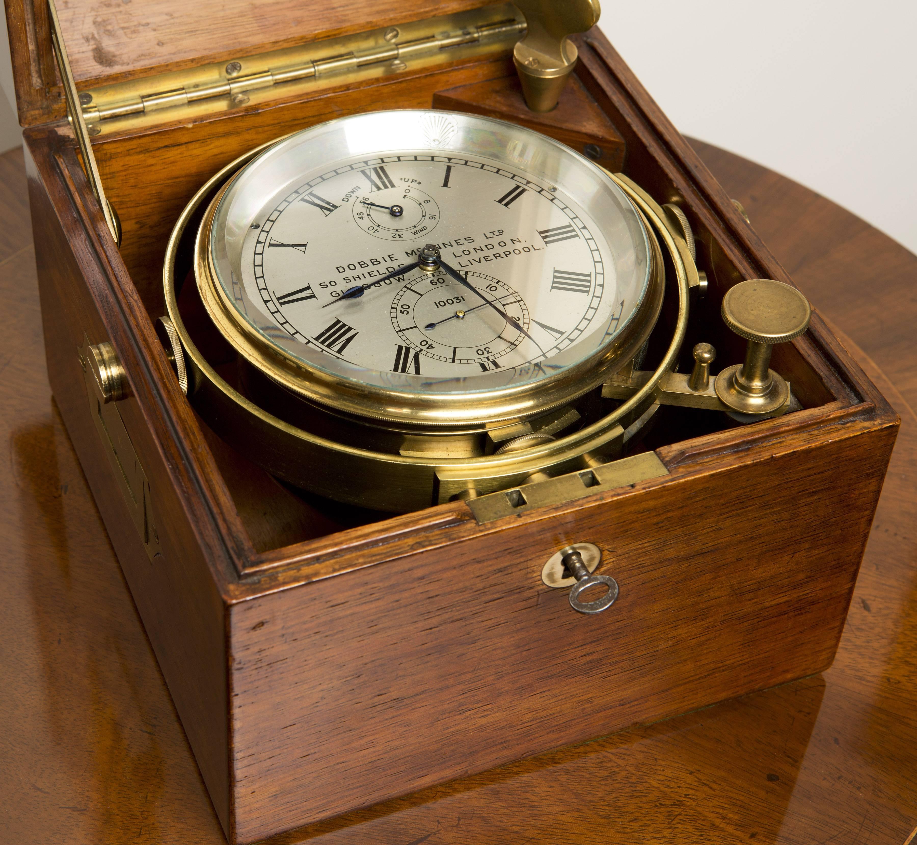 Marine Chronometer by Dobbie McInnes No. 10031.

Three-tier mahogany box with inset cartouche signed Dobbie McInnes Ltd 10031, Glasgow. Inset brass carrying handles, brass escutcheon to the base, ‘push button’ decorated brass knob opening the