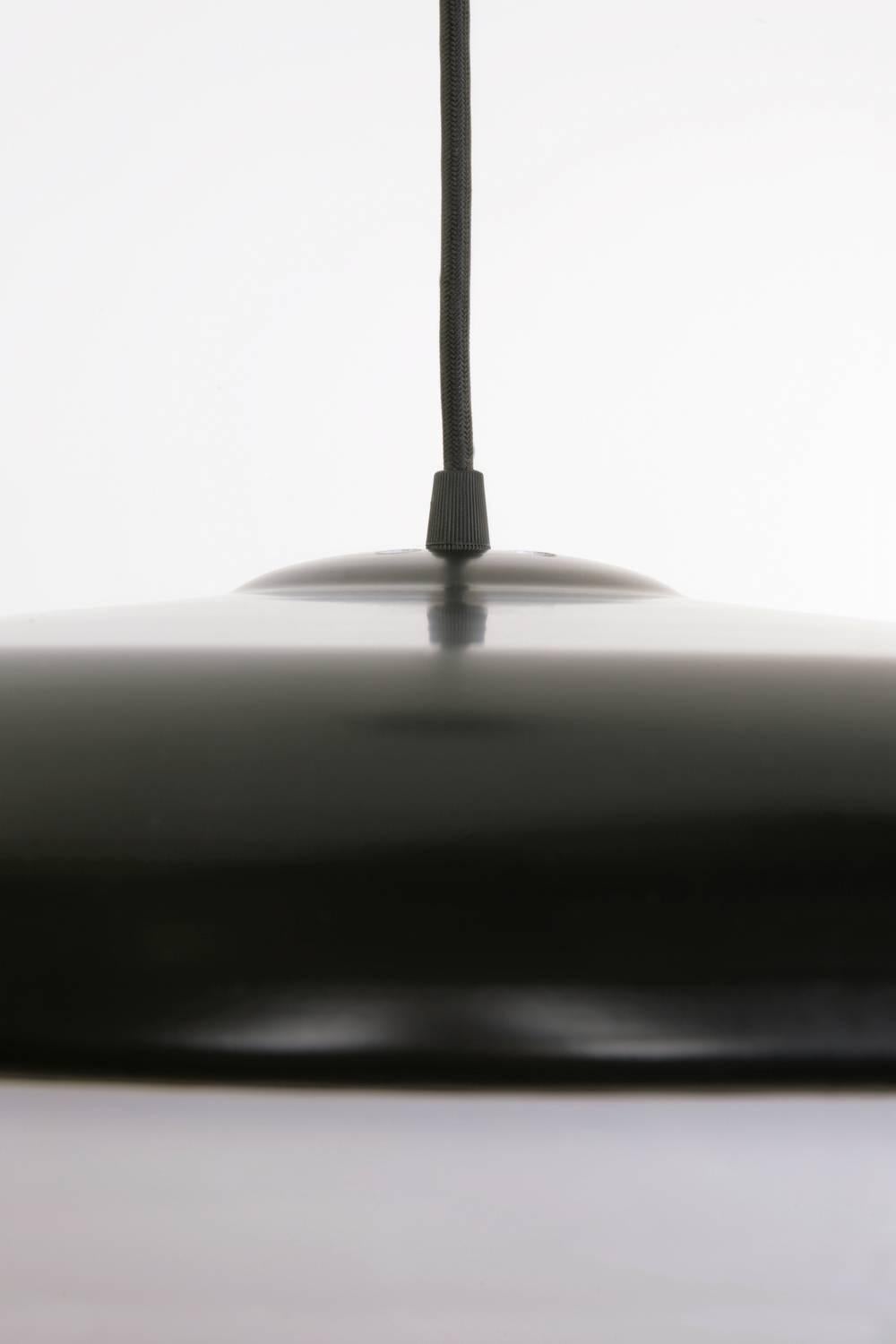 Der Sockel der Phare Pendelleuchte besteht aus gedrehtem Aluminium, ist schwarz pulverbeschichtet und hat einen weißen Lucite-Schirm. Die Pendelleuchte wird mit einer 6 Fuß langen schwarzen Stoffschnur geliefert und ist mit zwei mittelgroßen Sockeln