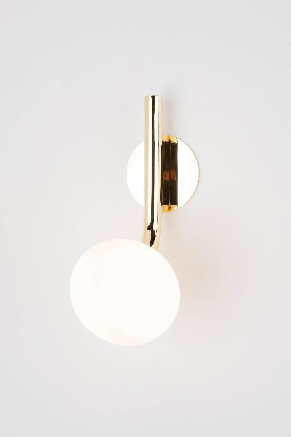 The graceful Etoile sconce is composed of a single curved limb providing a soft glow from the sand blasted, handblown glass shade. The backplate and stem are finished in both polished or satin brass, nickel and copper. The drop, and stems are