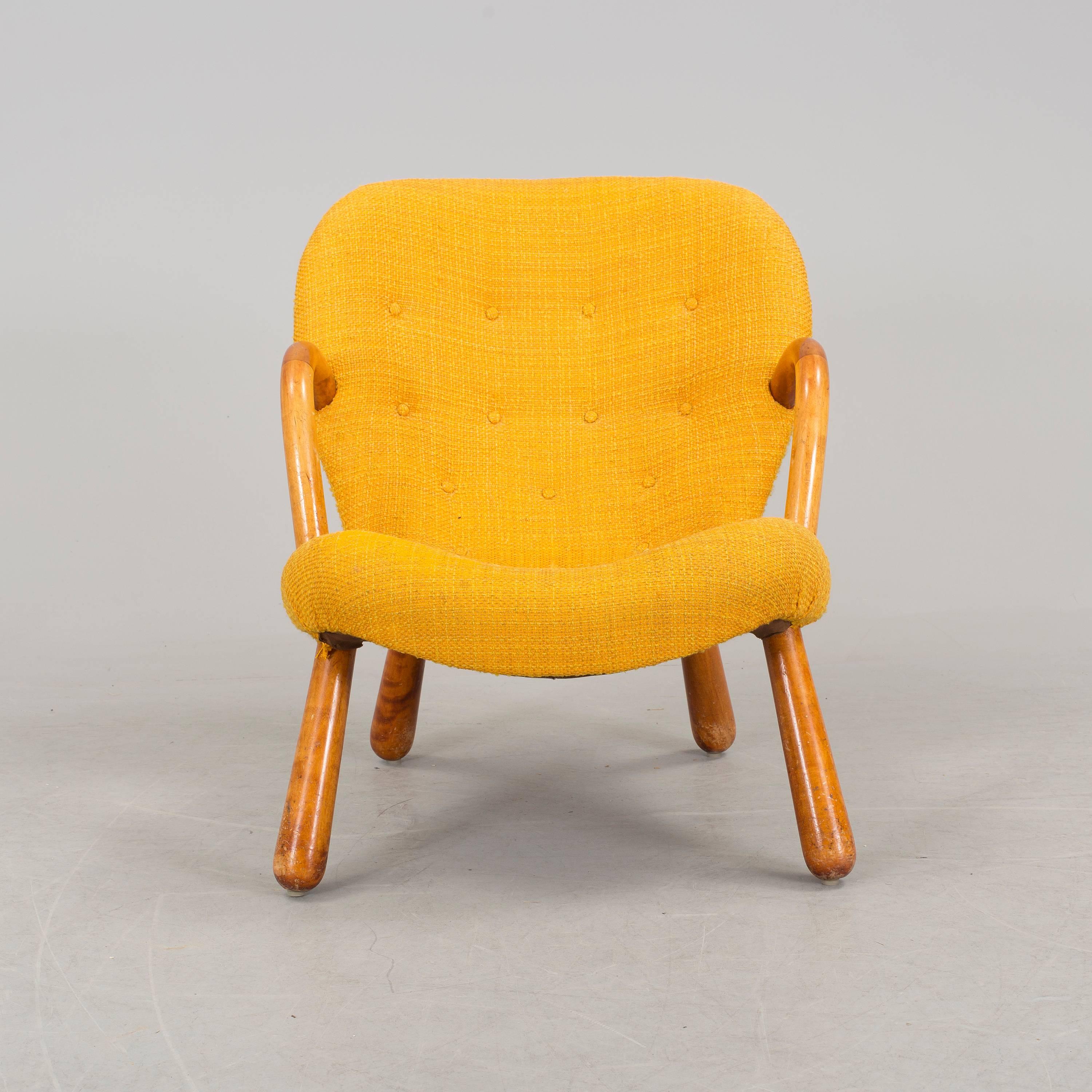 Clam chair with birch legs and yellow upholstery.