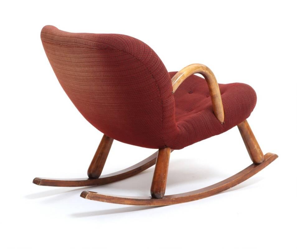“Clam” rocking chair with round beech armrests and legs. Seat and back upholstered with red colored fabric, fitted with buttons. Designed 1944. This example made 1940s by Nordisk Staal & Møbel Central.