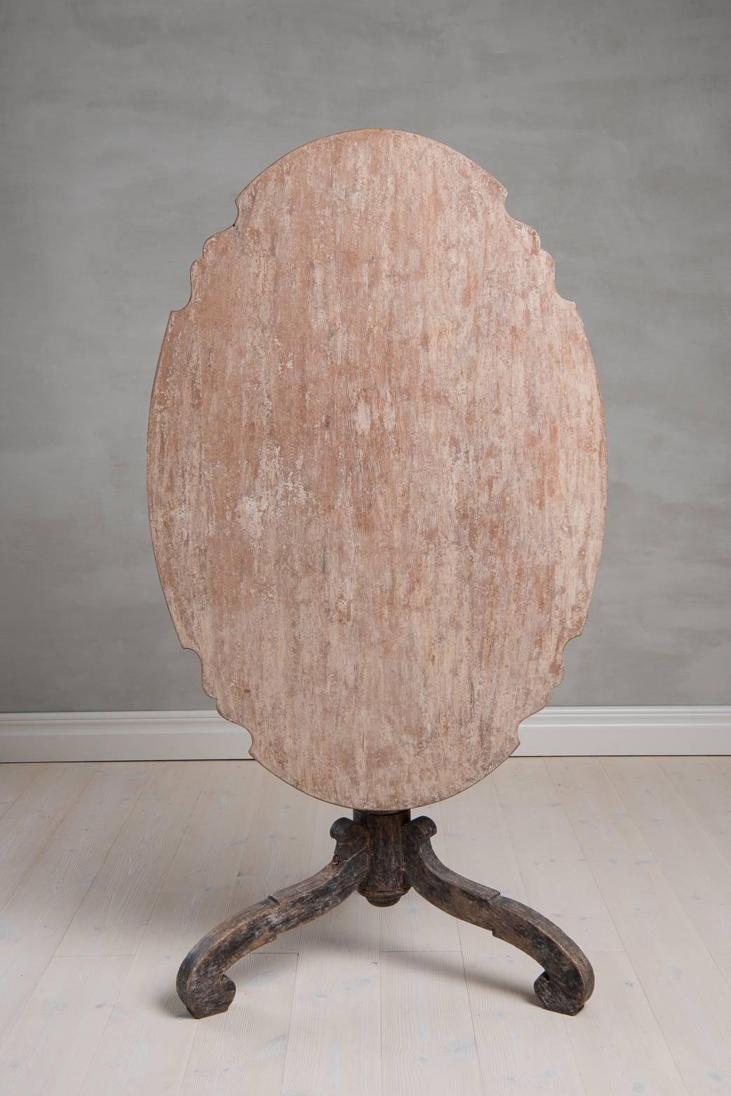 Large Swedish baroque oval tilt-top table from Northern Sweden. The table has a turned base supported by carved legs. The table is dry scraped to original paint and the lock mechanism is original to the table. Note the profiled edge of the table top