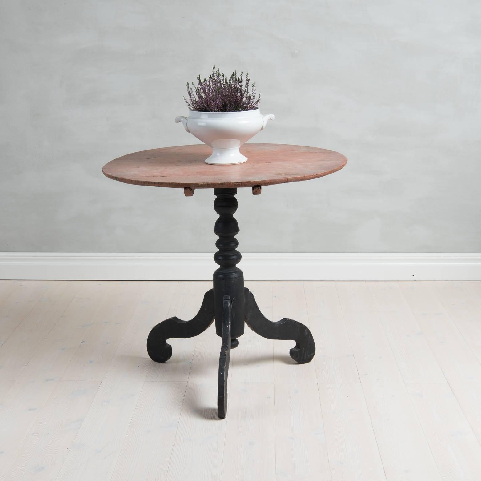 Tilt-top table with round tabletop with three turned legs on a curved foot. The table has original paint and is from Northern Sweden.