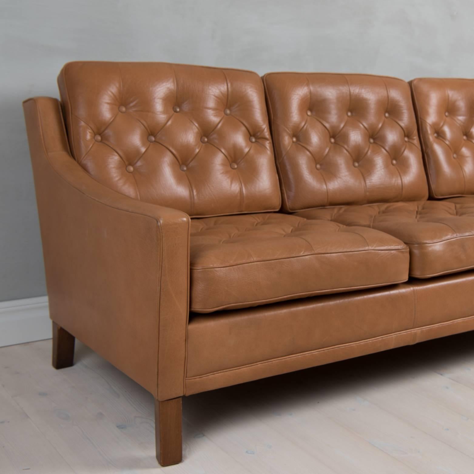 Sofa in leather manufactured by OPE furniture Sweden. Designed by Ib Kofod-Larsen. 
Three-seat sofa with lose leather-dressed cushions with buttons.