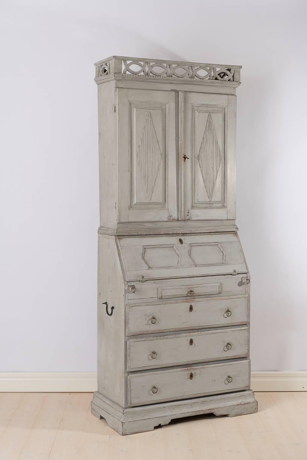 Top cabinet with ridged doors and unusual decorative interior. Bottom part with drawers and drop front desk. 
Original lock, key and side handles.