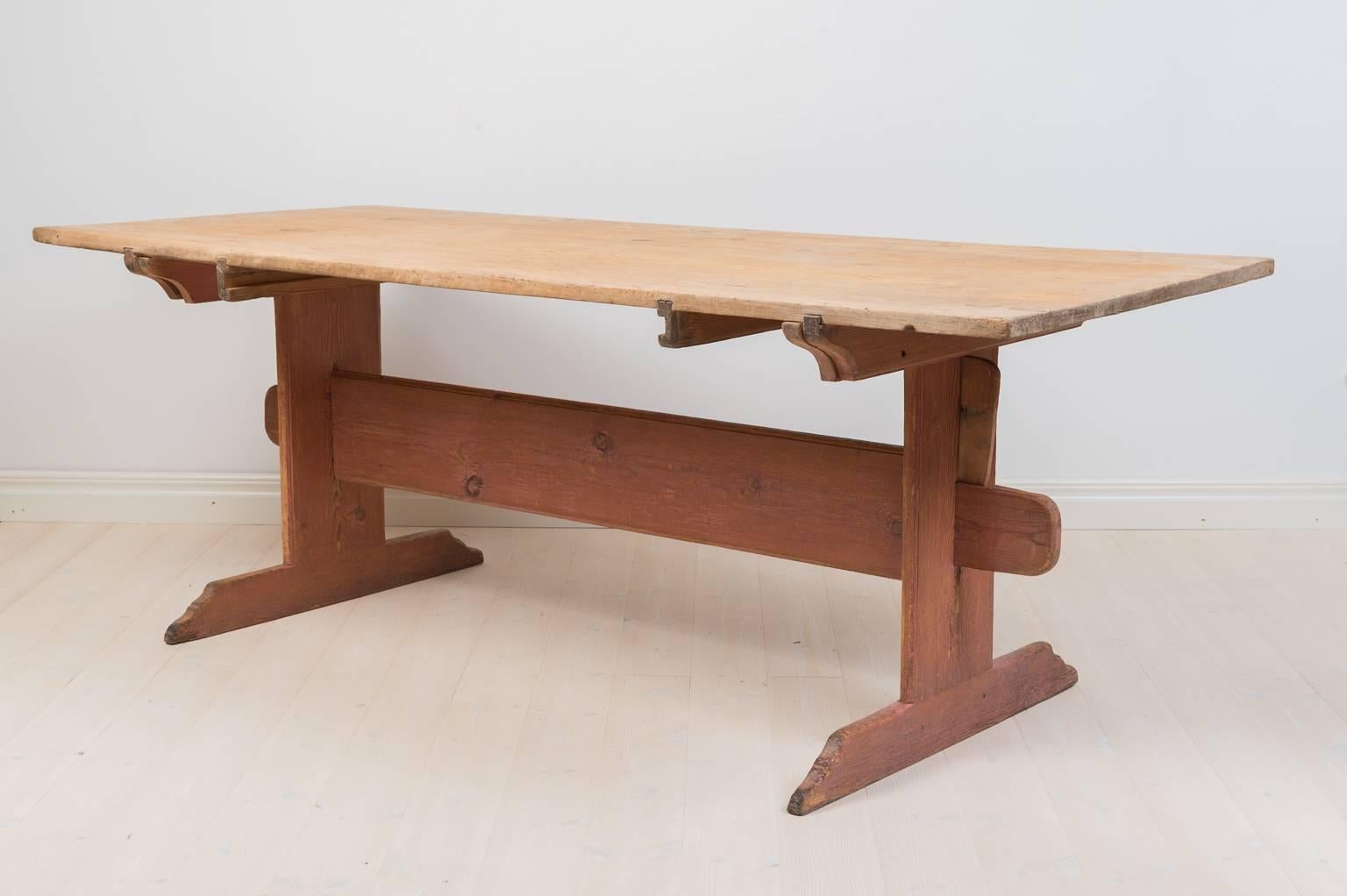 Trestle table in pine from northern Sweden. Leg frame and drawer had traces of the salmon colored original paint. The tabletop has an small older repair on the surface see picture.The table can be used both with and without the drawer.