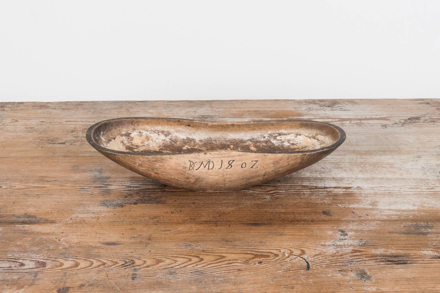 Wooden bowl in unusual oblong shape. It has the date 1807 carved in and also has initials, both that likely dates back to the first owner. The bowl has an old repair at the bottom in lead but otherwise is the condition good. The bowl has been used