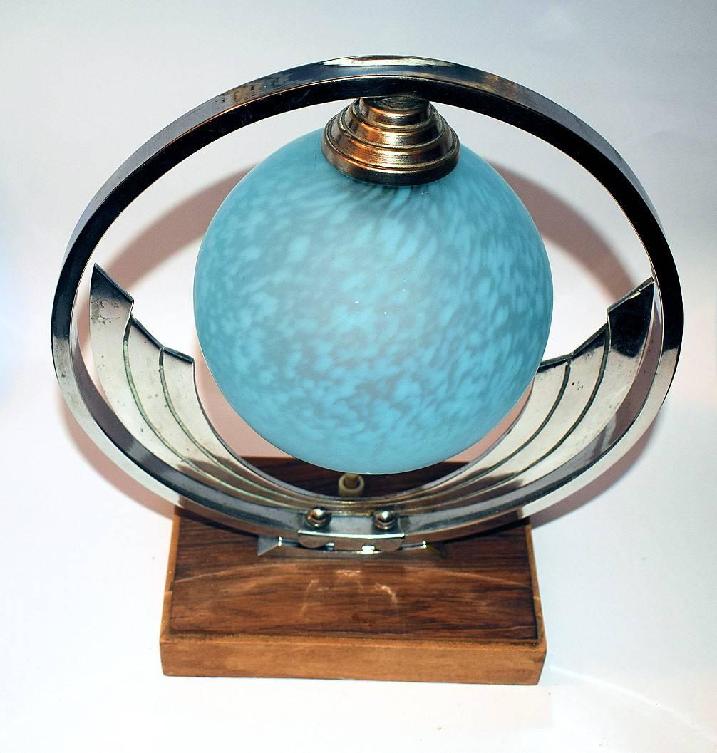 Diese stilvolle und absolut authentische Art-Déco-Tischlampe aus den 1930er Jahren stammt aus Frankreich. Ein verchromter Bügel umgibt den blau gesprenkelten Glasschirm, der auf einem Holzsockel ruht. Condit ist sehr gut mit minimalen Zeichen oder
