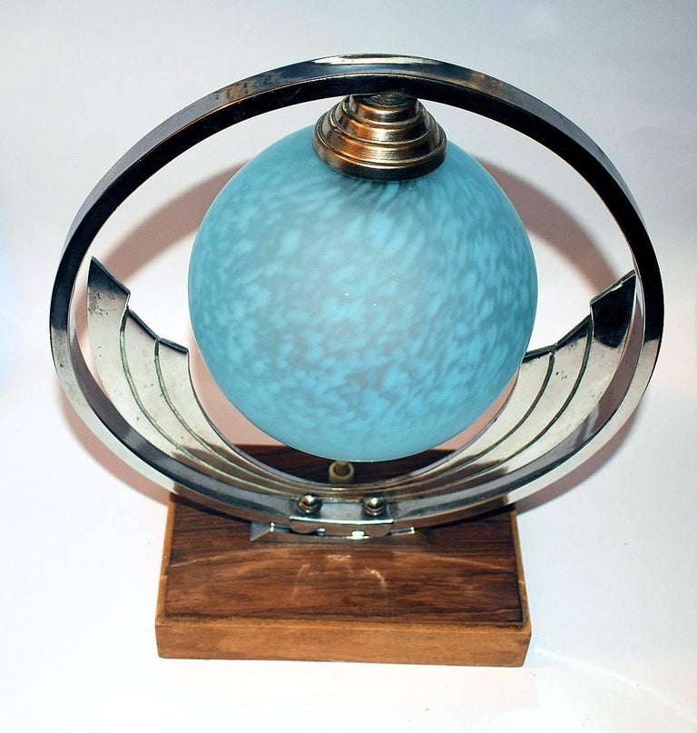 Originating from France is this stylish and totally authentic Art Deco table lamp dating to the 1930s. A chrome hoop encircles the mottled blue glass shade all of which is supported on a wooden base. Condition is very good with minimal signs or age.