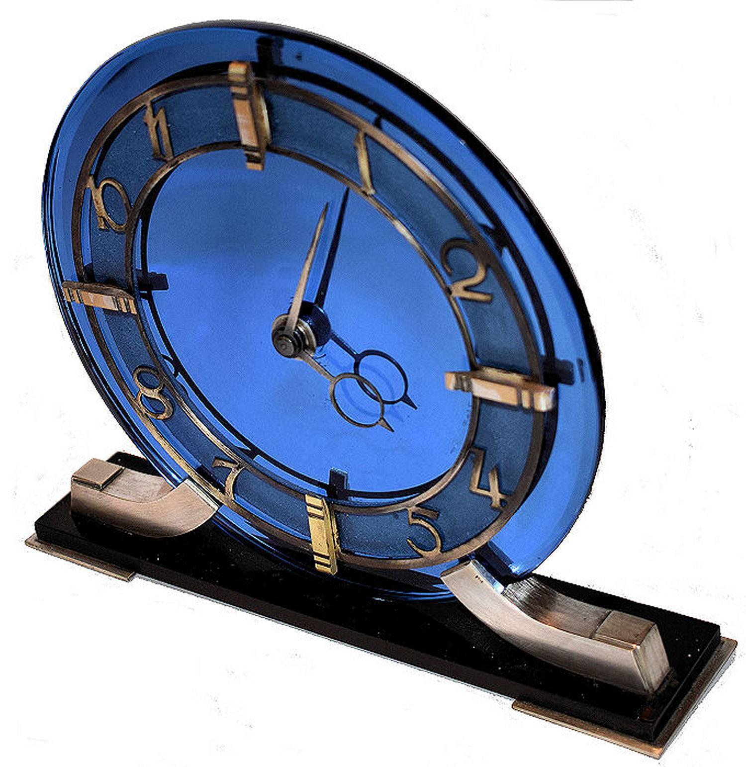 Very attractive and glamourous 1930s Art Deco Modernist clock by Smiths, an English maker. Runs on electric so no winding needed. Features a heavy thick blue mirror glass face with gilded Bezel and black plinth. The condition is excellent, showing