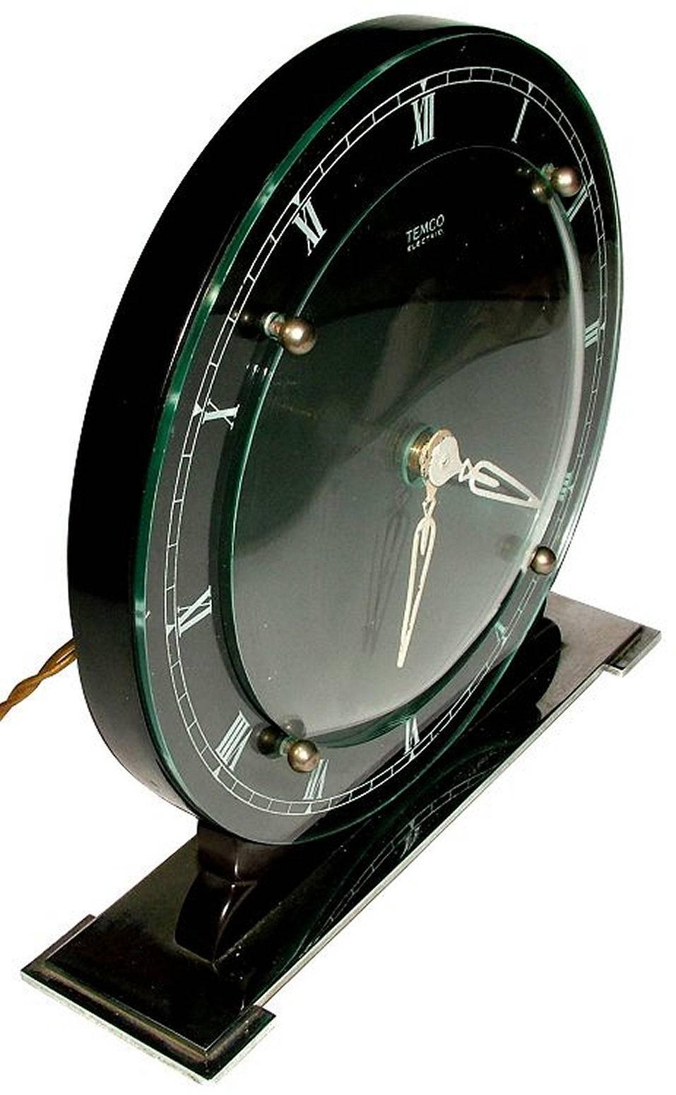 Lovely Art Deco glass and chrome electric mantel clock stepped base by Temco.
Gorgeous looking clock and one we think would ideal for any man cave out there or perhaps office. The main clock body is made from ebonized wood with a convex glass front