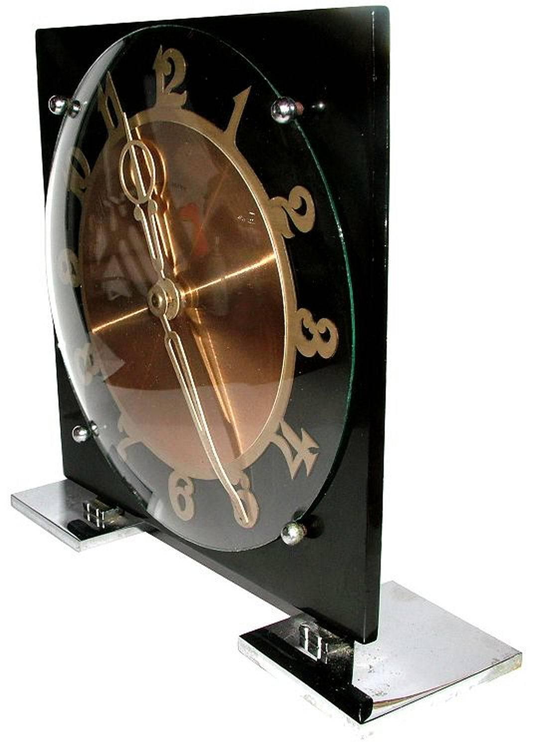 Very attractive 1930s Art Deco English modernist clock by Temco. Features a chrome back and feet with early plastic black face with gilt numerals and central dial. Very distinctive looking clock, a fabulous timepiece for any setting or room.