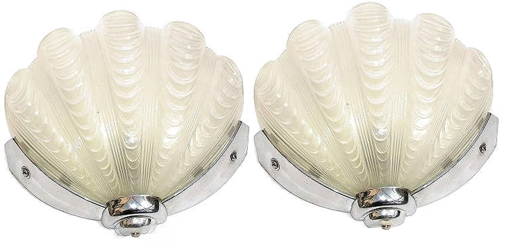 A beautiful matching of Art Deco wall lights of shell form. The chrome frames are in very good original condition which when fitted to the wall hold the beautiful white shades firmly in place. Truly beautiful and will work perfectly with the most