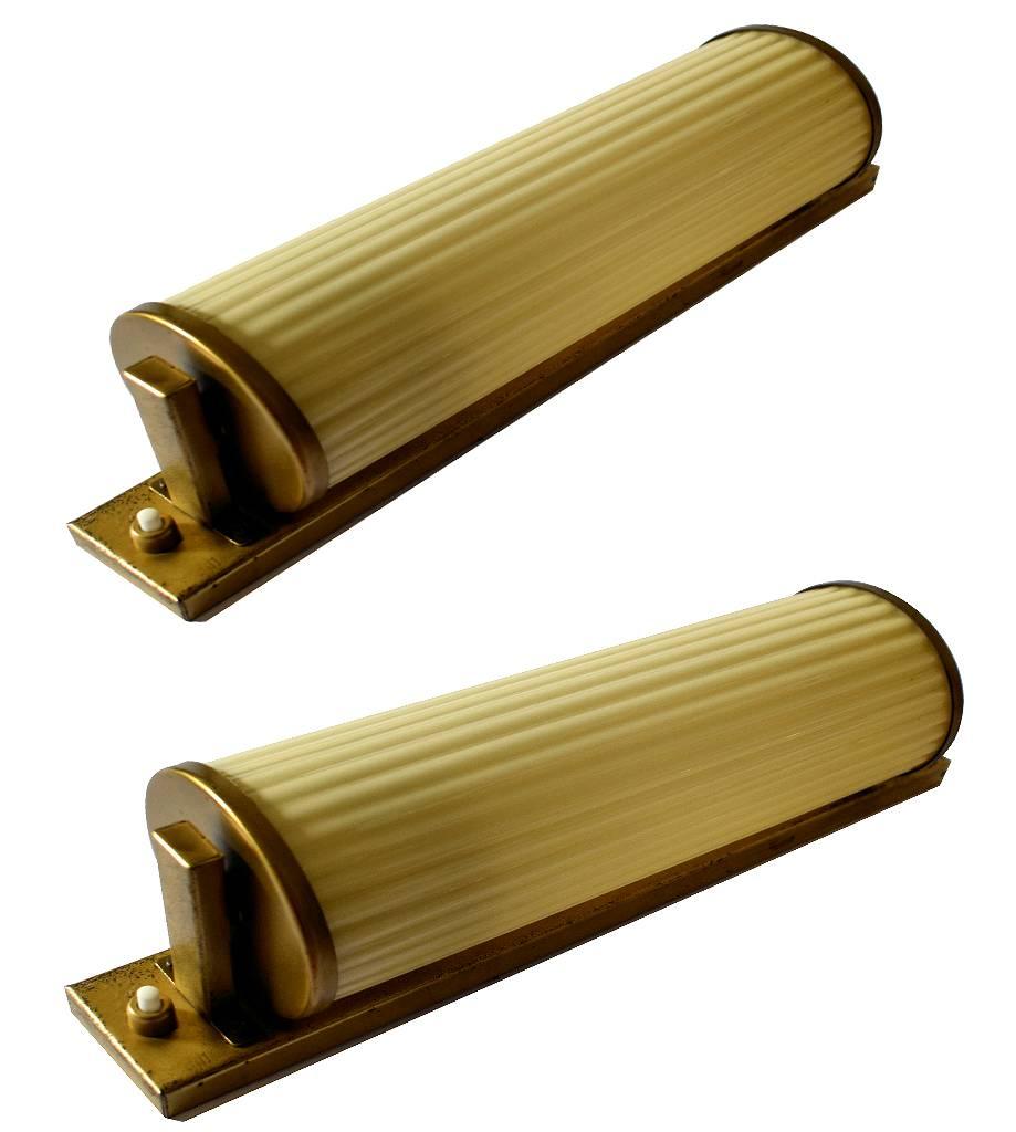 Fabulous pair of 1930s Art Deco glass wall lights on gilded metal back plates. Originating from Belgium these lights are a mirror match and feature tubular glass shades which are ribbed and in a soft sepia toned cream color. The back plates are