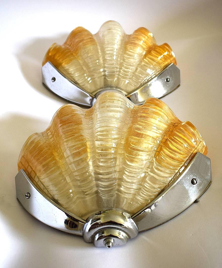 A beautiful pair of two matching Art Deco wall lights of shell form. The chrome frames are in very good original condition which when fitted to the wall hold the beautiful yellow and white shades firmly in place. Truly beautiful and will work