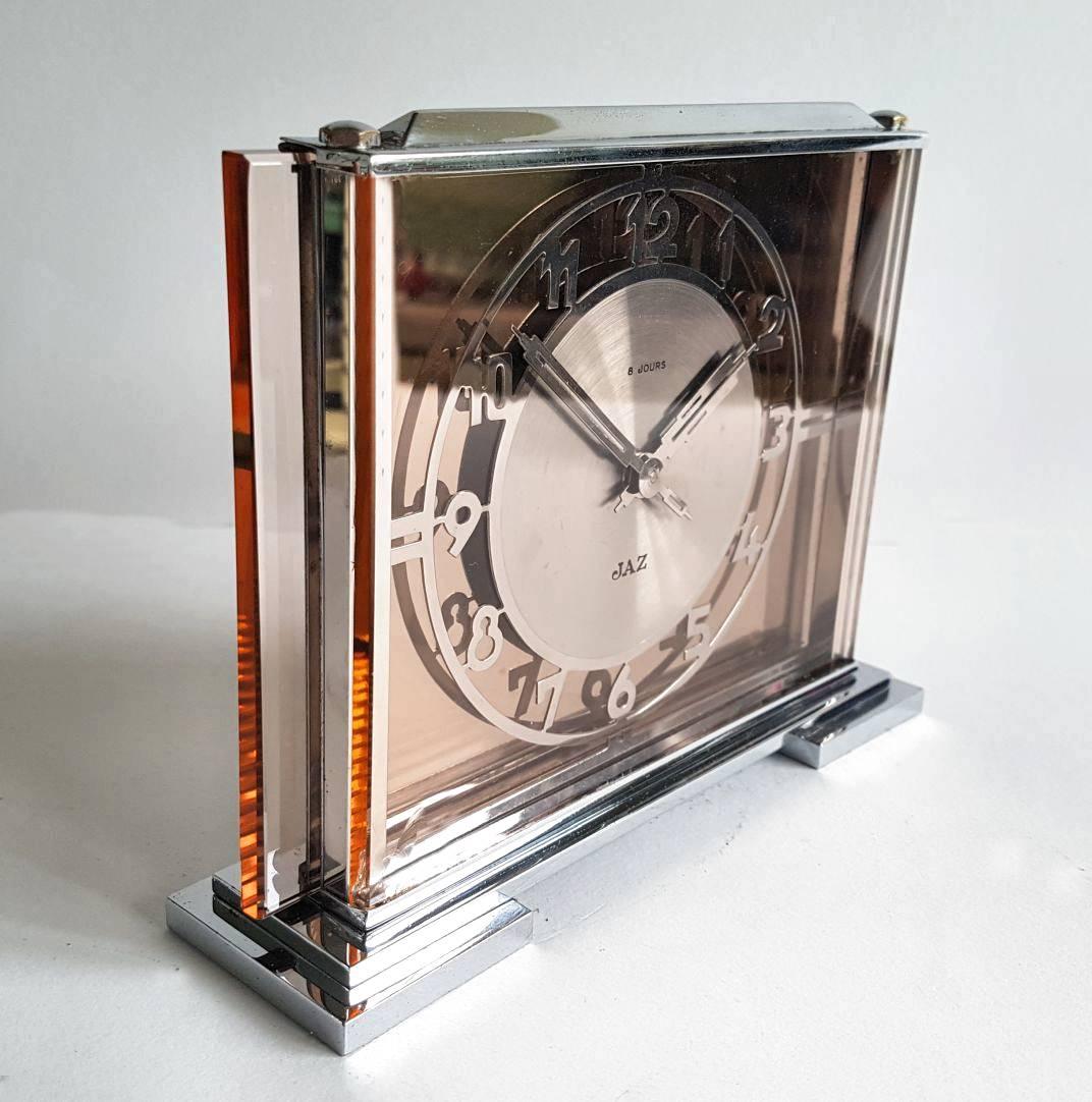 Rare 1930s Art Deco glass and chrome clock by JAZ. Originating from France this clock is the epitome of glamorous. Heavy weight chrome plinth with thick panes of glass making up the dial mount. Fretted out stylized Art Deco numerals finishes this