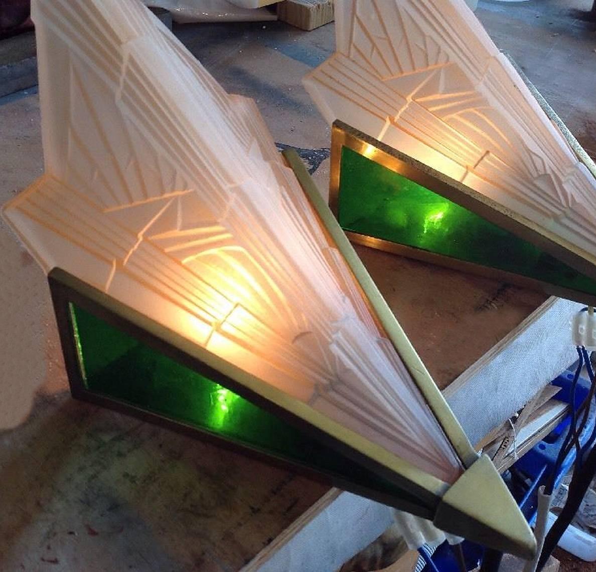 A rare chance to gain these rare and stylish pair of 1930s Art Deco wall lights. Blush pink geometric moulded and frosted glass slip in shades, lacquered brass fittings with emerald green glass side slips, period Ediswan brass bulb holders with