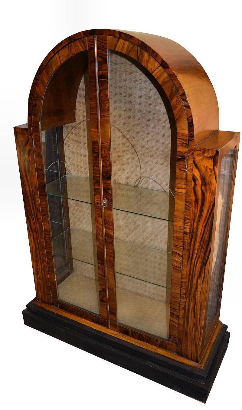 A truly beautiful 1930s Art Deco walnut cabinet of great proportions. The veneers on this cabinet are exceptional and looks very impressive. The Arched top tapers down to a ebonised stepped plinth. The interior still retains its original cloth