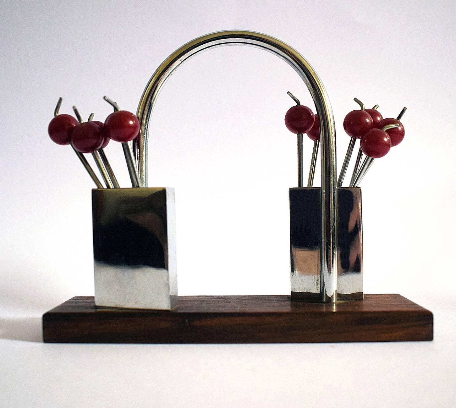 A charming 1930s, cocktail set originating from France. Features cherry red bakelite cocktail sticks with chromed metal prongs, all contained within two chrome boxed holders on a rosewood base. Great set in very good condition, minimal signs of age.