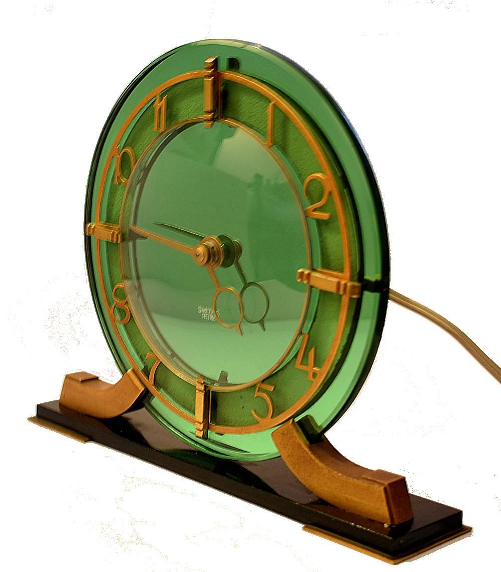 Superb 1930s Art Deco mantel clock by Smiths. Heavy thick green mirror glass with gold tone stylized deco numerals. Beautiful condition throughout, No chips or scratches. Full working order with long flex and Bakelite plug. Single knob at rear