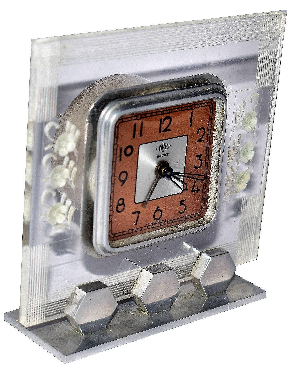 French Art Deco Acrylic clock by the French clock makers DEP this model is called SAVOY.
The case is transparent early plastic with etched decoration each side The is dial two-tone in silver and salmon pink with a glass domed cover. The clock has