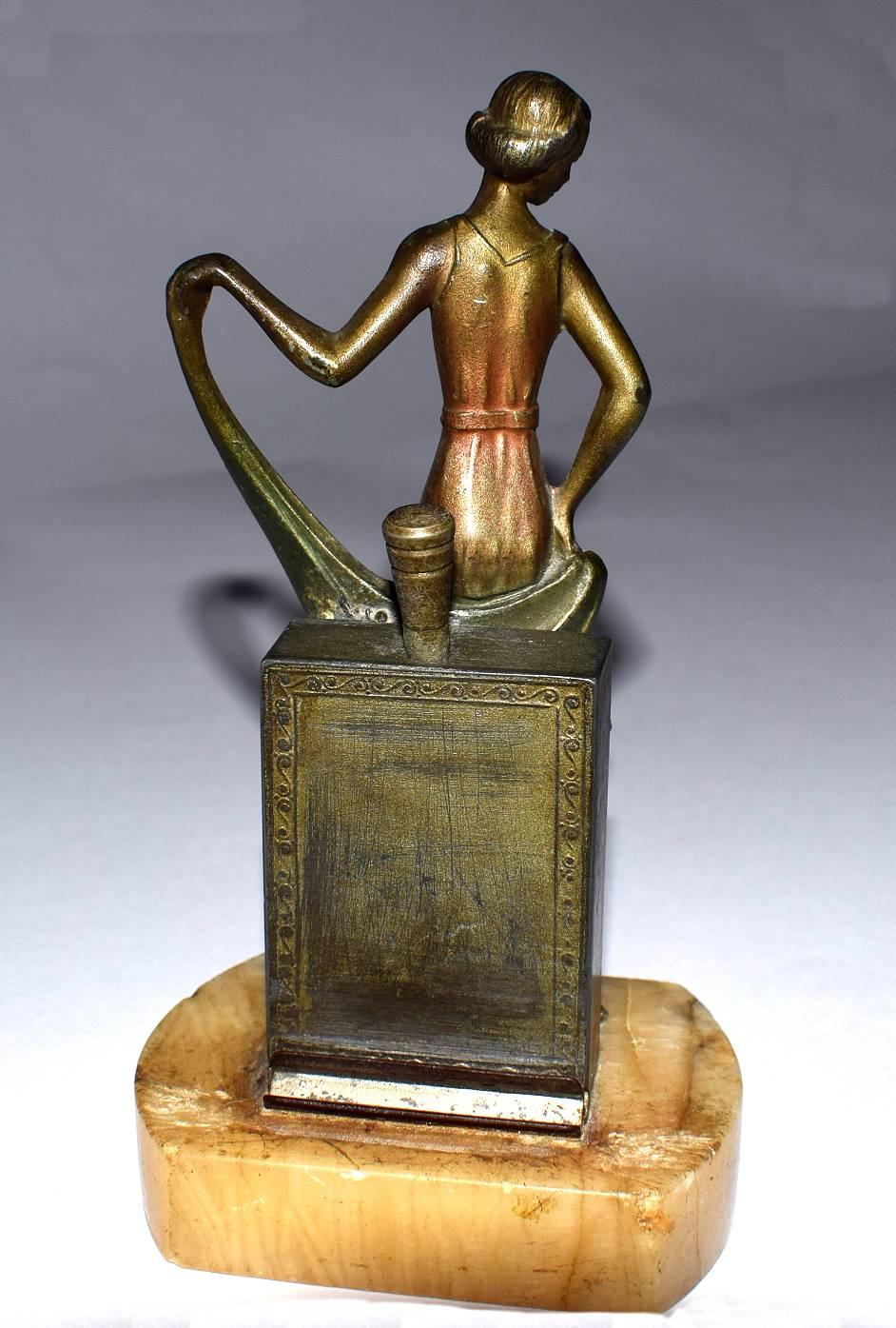Delightful 1930s table lighter depicting a young lady. She's made from spelter and cold painted on top. Quite a weighty little item considering it's size. There is a dauber to the back and a recess resting area, not completely sure how it works but