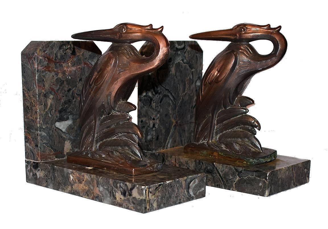 Very stylish and rare matching pair of bookends. These are a great find and in exceptional condition. Originating from France both stand on marble bases and depict stylized birds in spelter which have been cold painted and rest of solid marble.