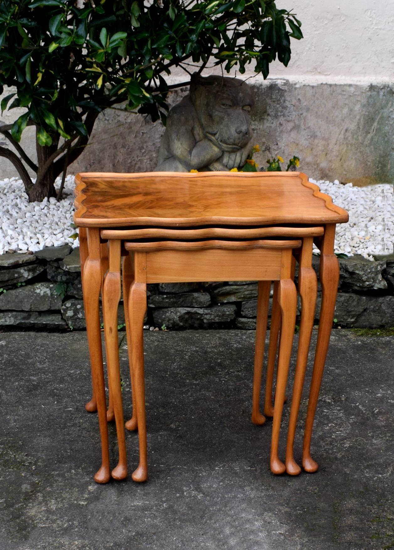 This is a beautiful 1930s Art Deco blonde walnut nest of three tables with a shapely edging and a pleasant light medium colour to the finish. Each table sits snuggly underneath each other and slides effortlessly out when you have guests. These would